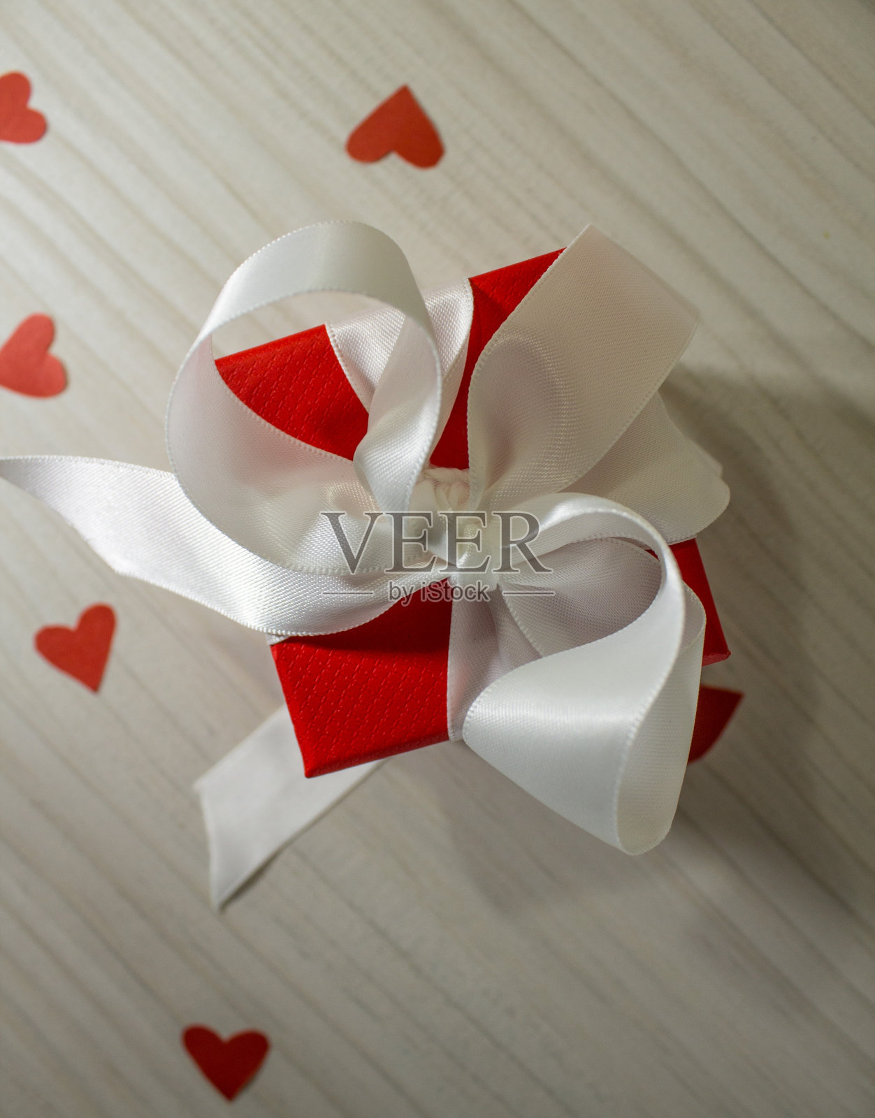 白色背景上有一个蝴蝶结的红色礼盒，桌上有一颗心照片摄影图片