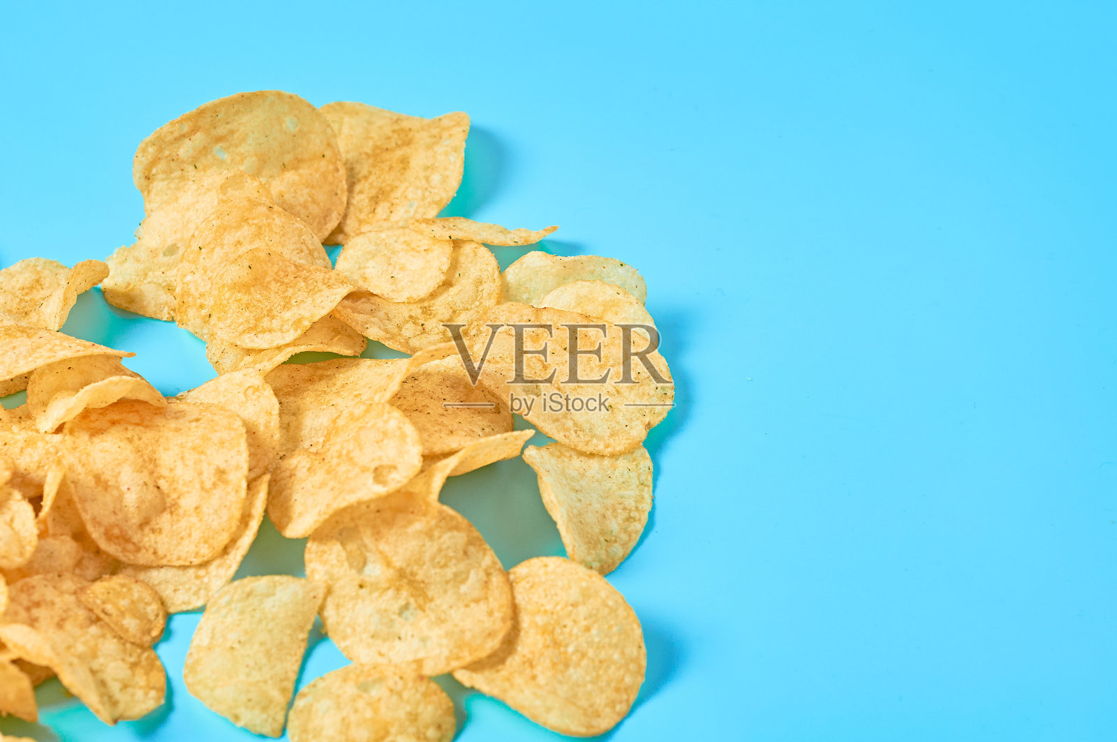 蓝色背景上散落着许多炸土豆片。空间的文本照片摄影图片