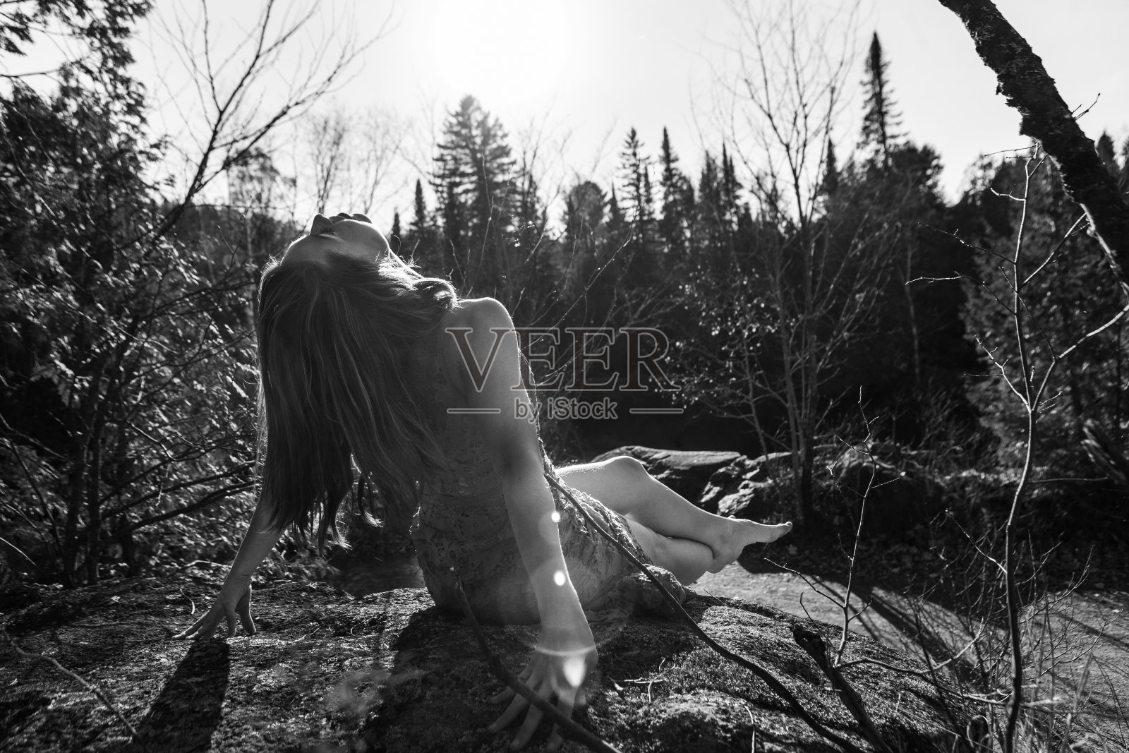 年轻的女人穿着衣服在一个完美的一天在阳光下摆姿势的岩石上照片摄影图片