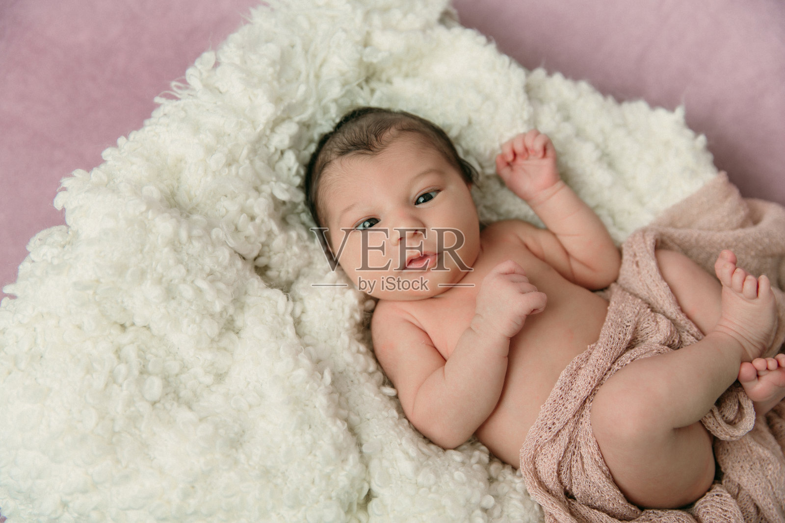 粉红色的背景下苏醒的新生女婴照片摄影图片