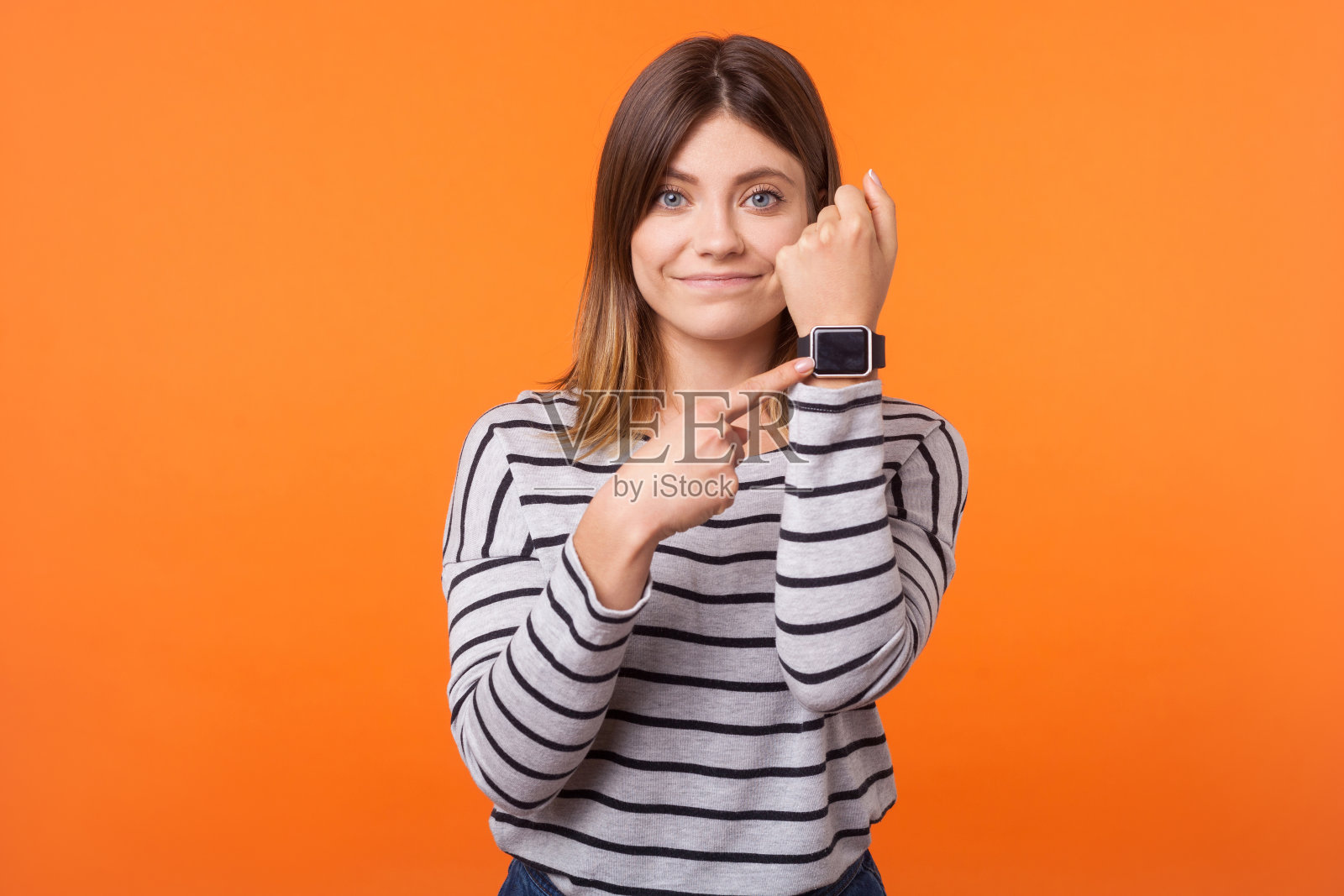 肖像的不耐烦积极的女人棕色头发在长袖条纹衬衫。室内工作室拍摄孤立的橙色背景照片摄影图片