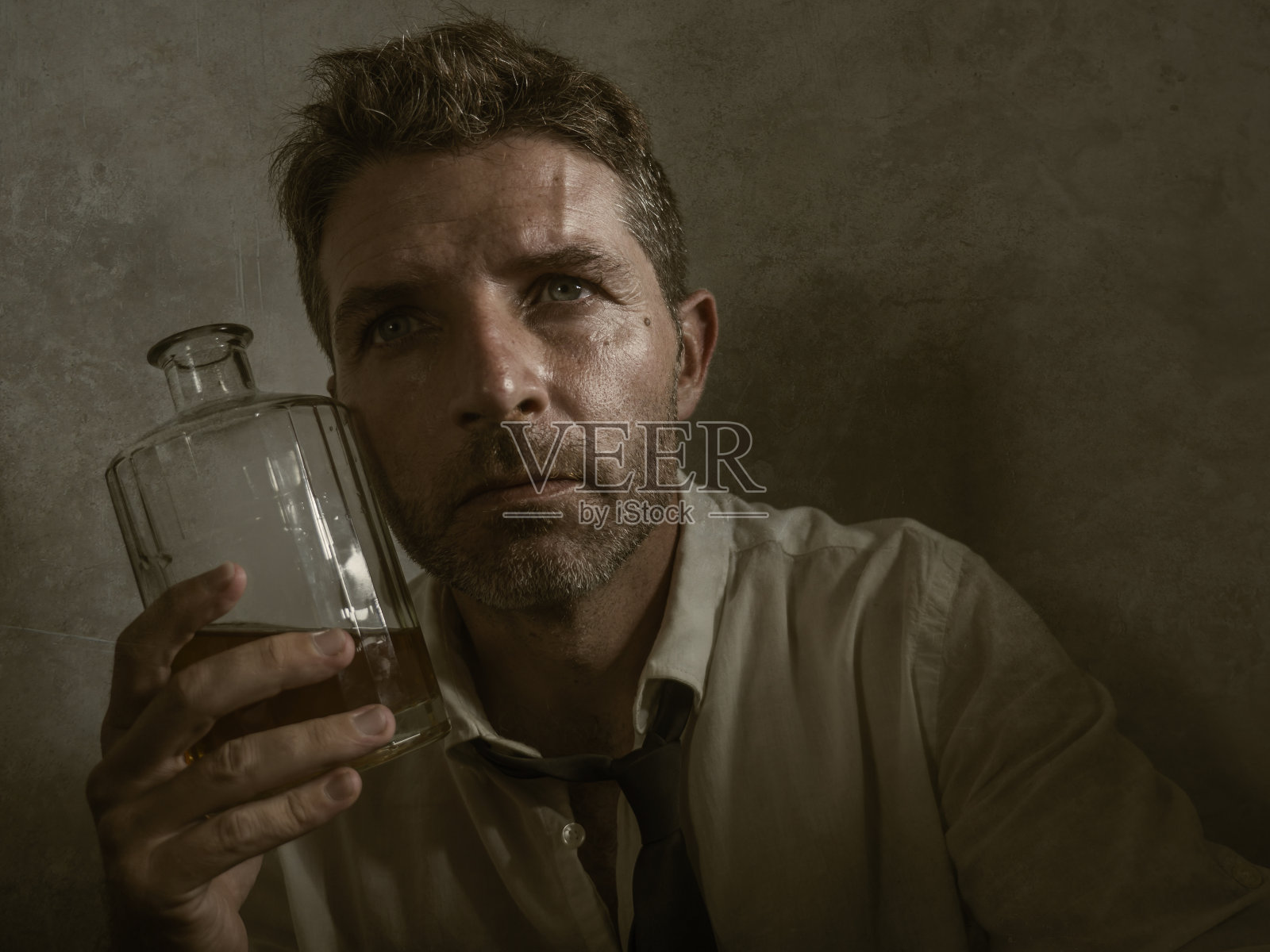 30-40岁醉酒男人的戏剧性肖像，松开领带，绝望地喝着酒，拿着威士忌酒瓶，感到恶心和沮丧，借酒消愁的颓废风格照片摄影图片