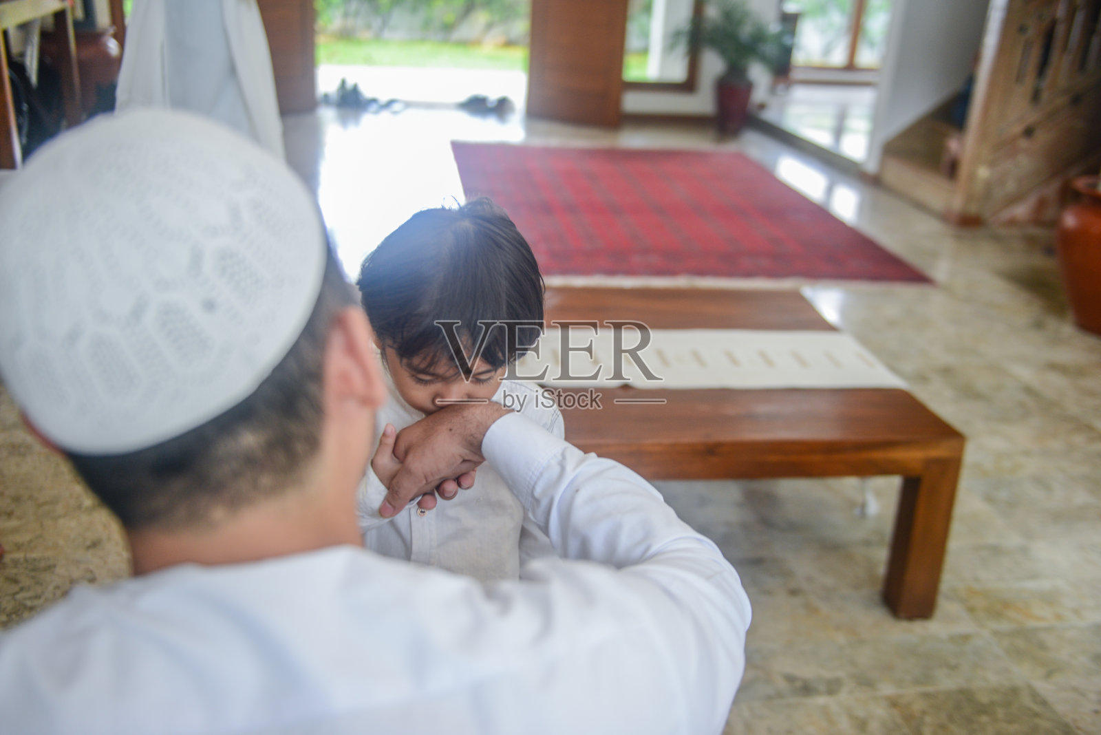 亚洲穆斯林男孩亲吻她父亲的手在Hari Raya Puasa庆祝照片摄影图片