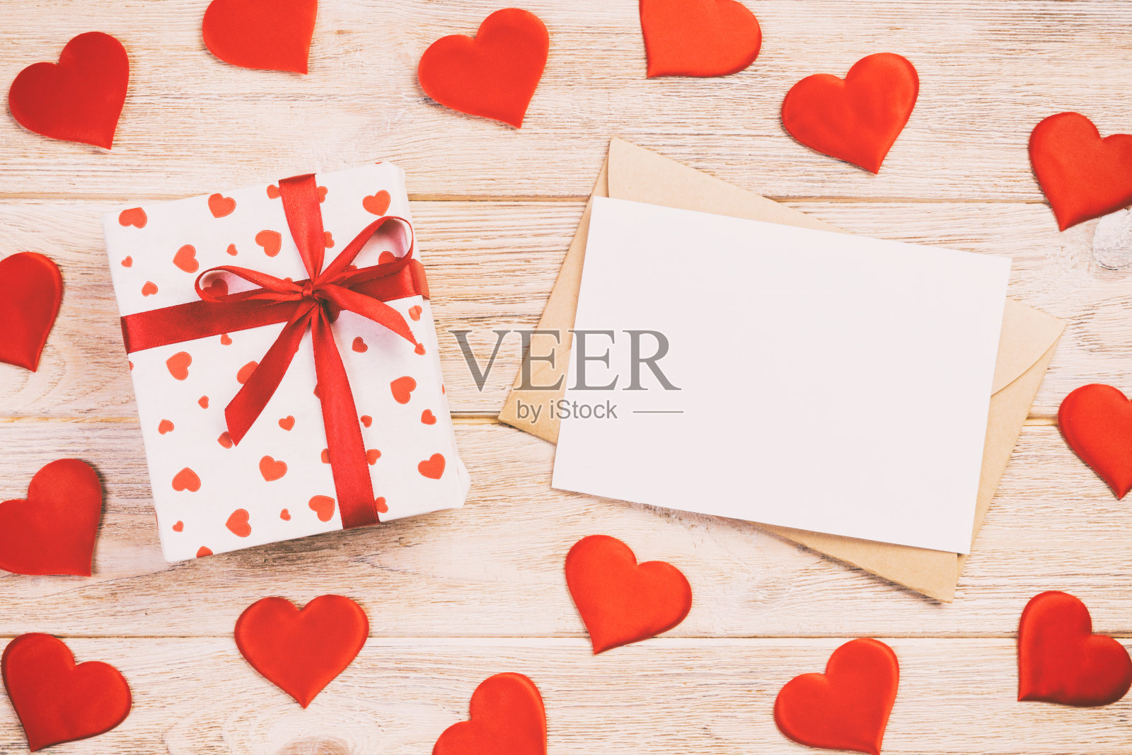 橙色木质背景上的红色爱心信封和礼盒，情人节贺卡、爱情或婚礼祝福概念照片摄影图片