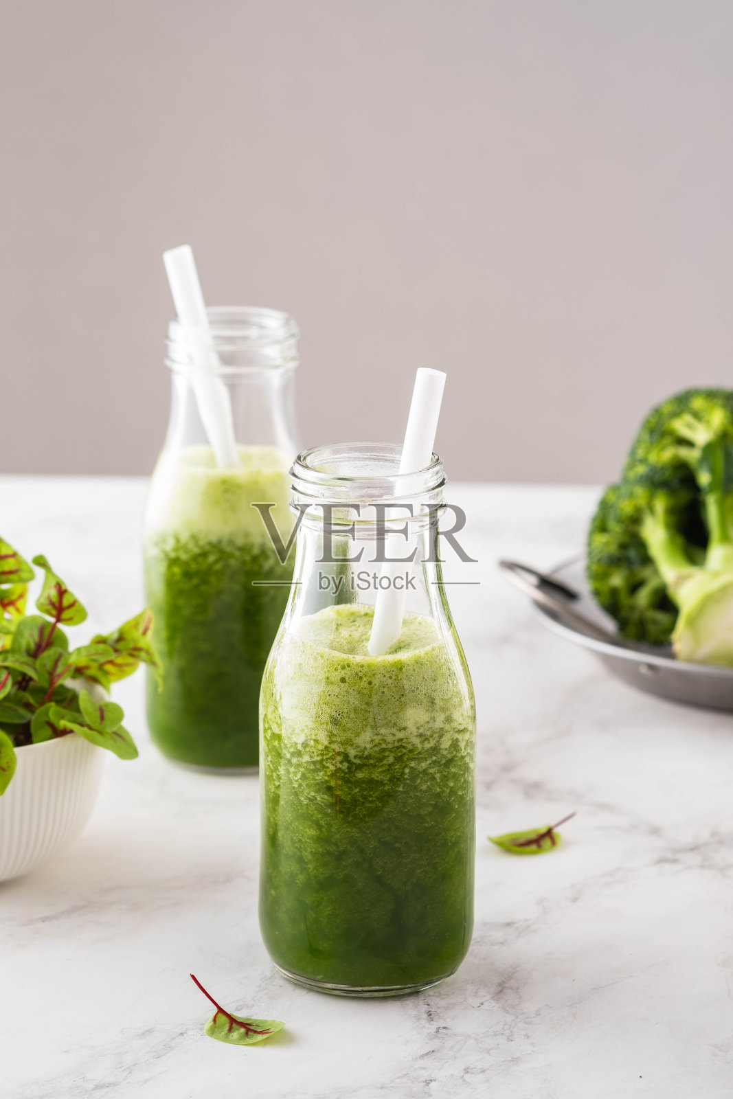 混合的绿色冰沙和配料在白色的桌子上。照片摄影图片