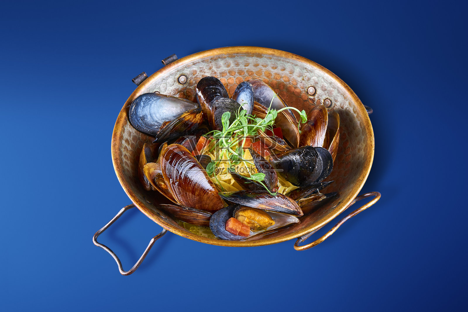 近距离观看美味的碗与贻贝在贝壳孤立在蓝色。美味的海鲜开胃菜照片摄影图片