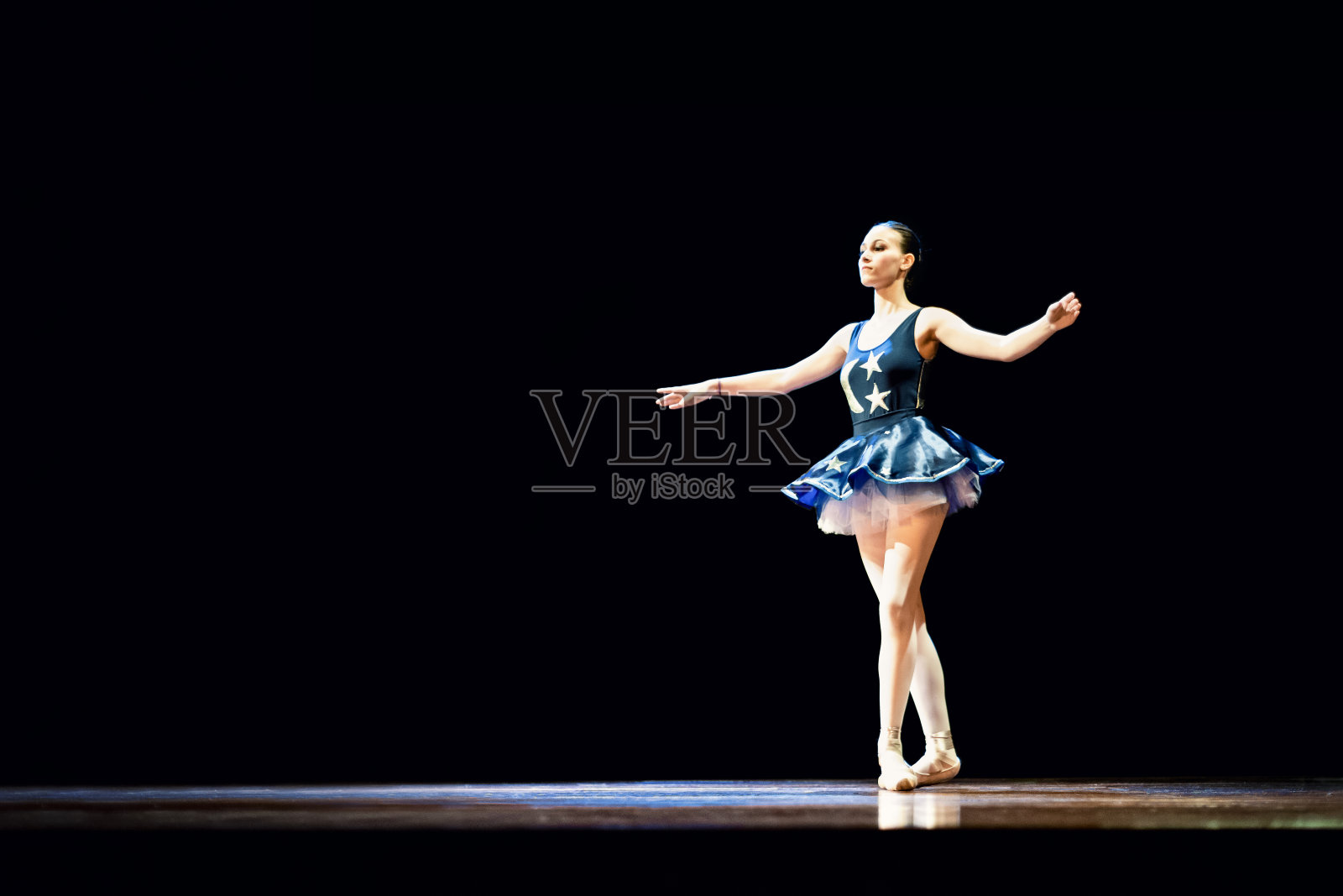 年轻女孩在黑暗的舞台上跳芭蕾舞照片摄影图片