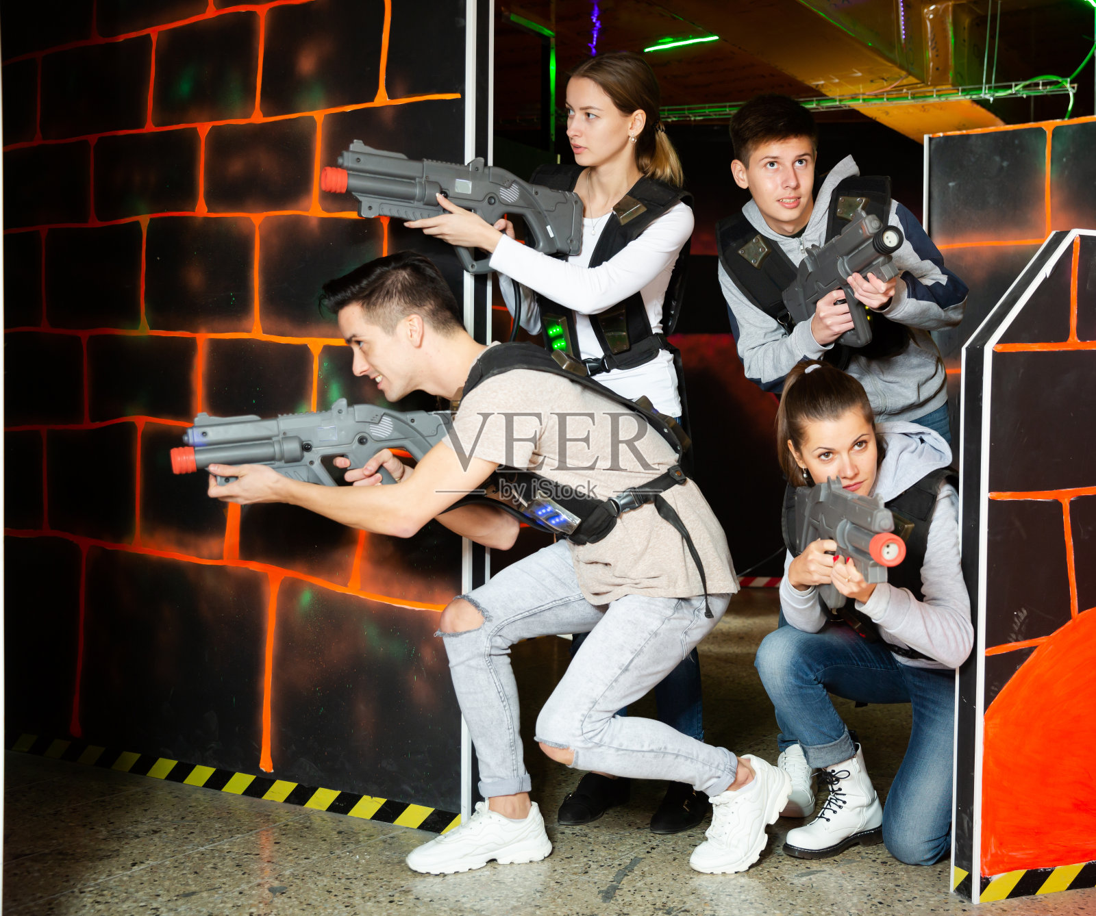 兴奋的年轻人热情地玩激光标签游戏，两队在黑暗的房间里对战照片摄影图片