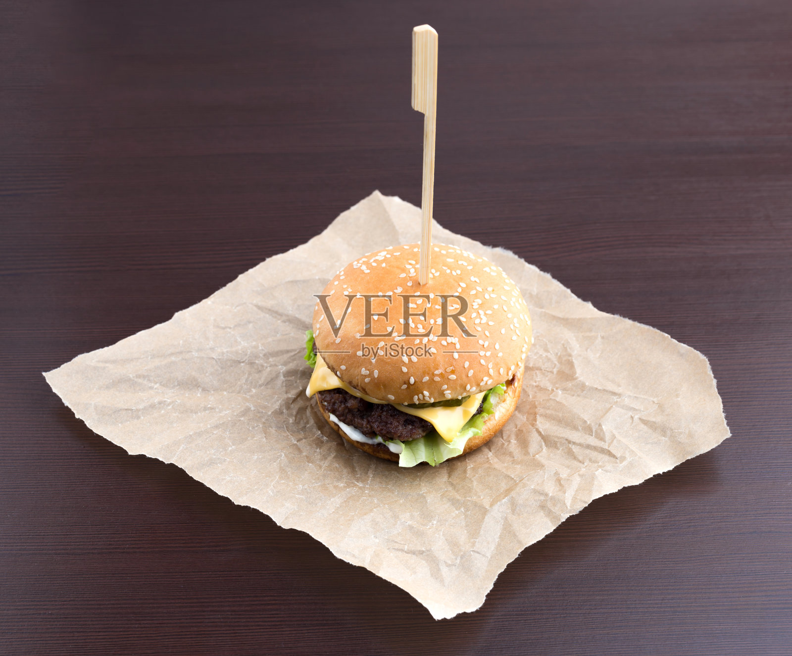 烤羊皮纸上的汉堡。牛肉肉饼，切达奶酪，生菜，培根，番茄和香醋沙司。照片摄影图片