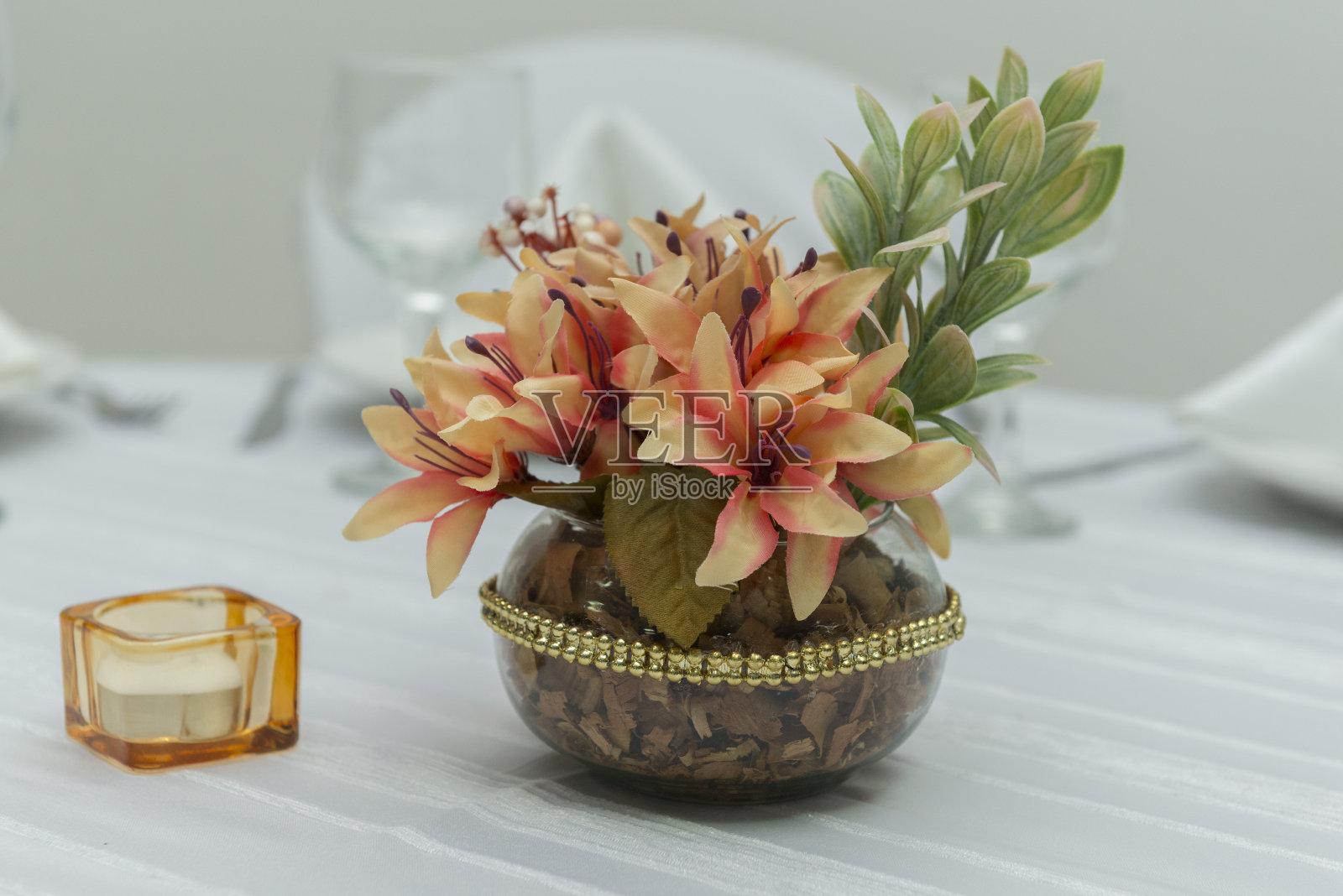 餐桌上，一根蜡烛旁边，漂亮的花瓶里插着装饰性的鲜花。简单的结婚纪念日装饰。文本区域。Copy space选择焦点。照片摄影图片