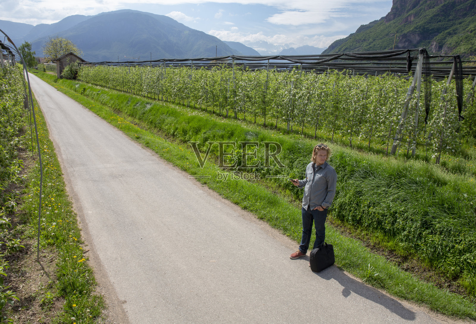 一个年轻人在果园里的乡间路上等待骑乘照片摄影图片