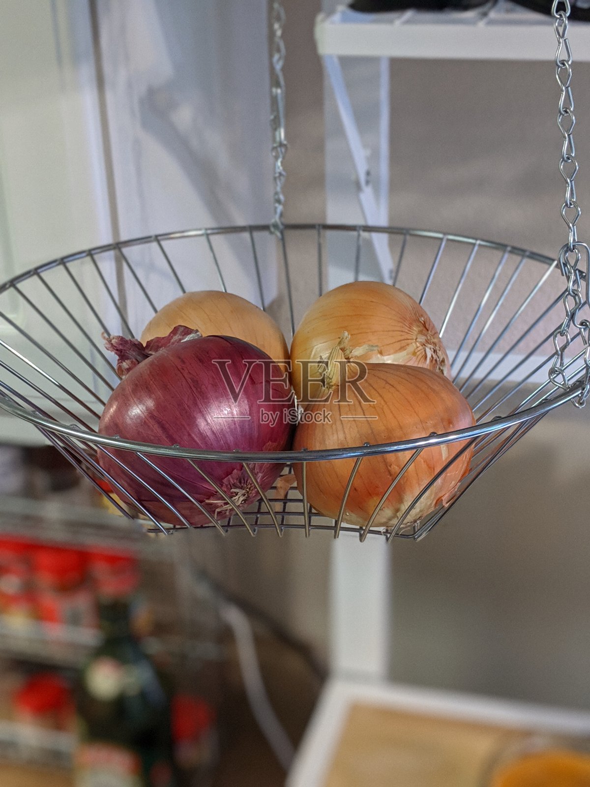 厨房里的金属挂篮，里面装着洋葱照片摄影图片