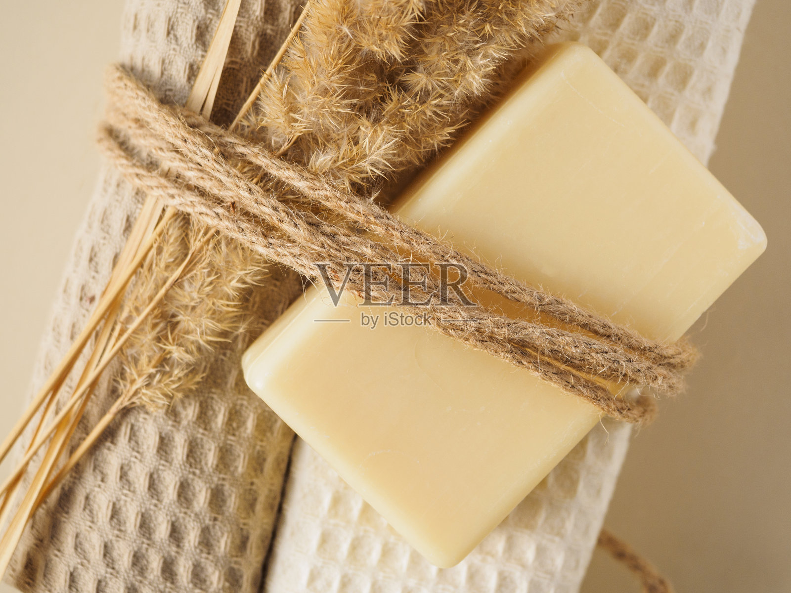 手工制作的肥皂、毛巾和干燥的耳朵用绳子连接在米色的背景上照片摄影图片