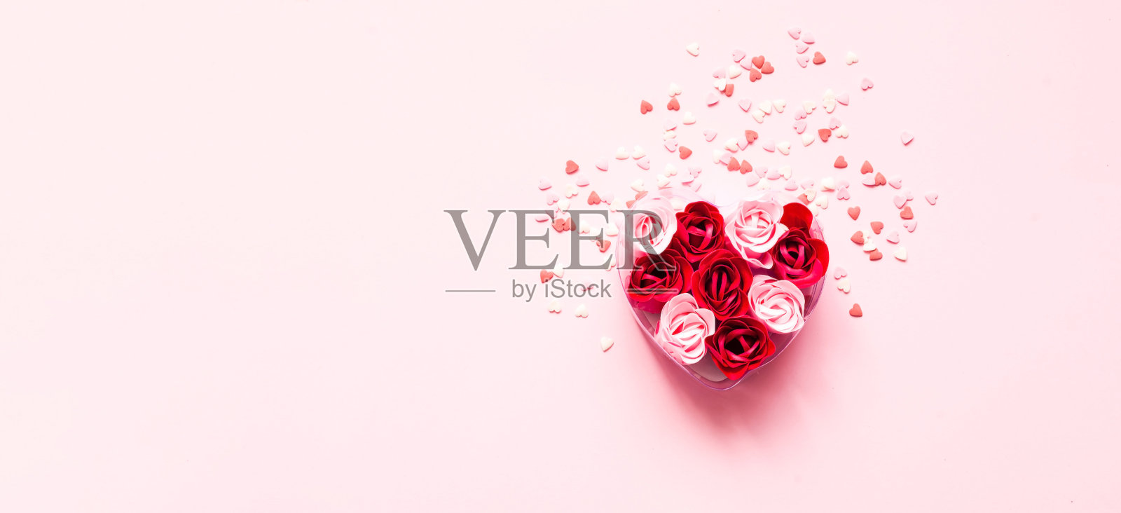 情人节。心形的玫瑰花瓣在粉红色的背景和甜蜜的纸屑。节日的概念。特写镜头照片摄影图片