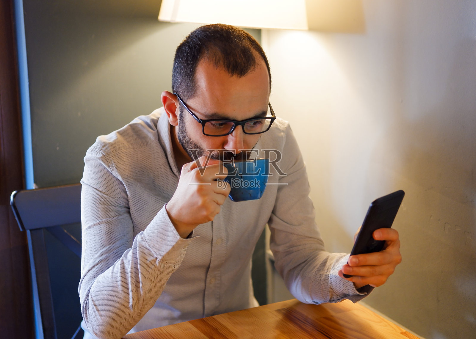 一个漫不经心的男人用手机拿着咖啡的特写照片摄影图片