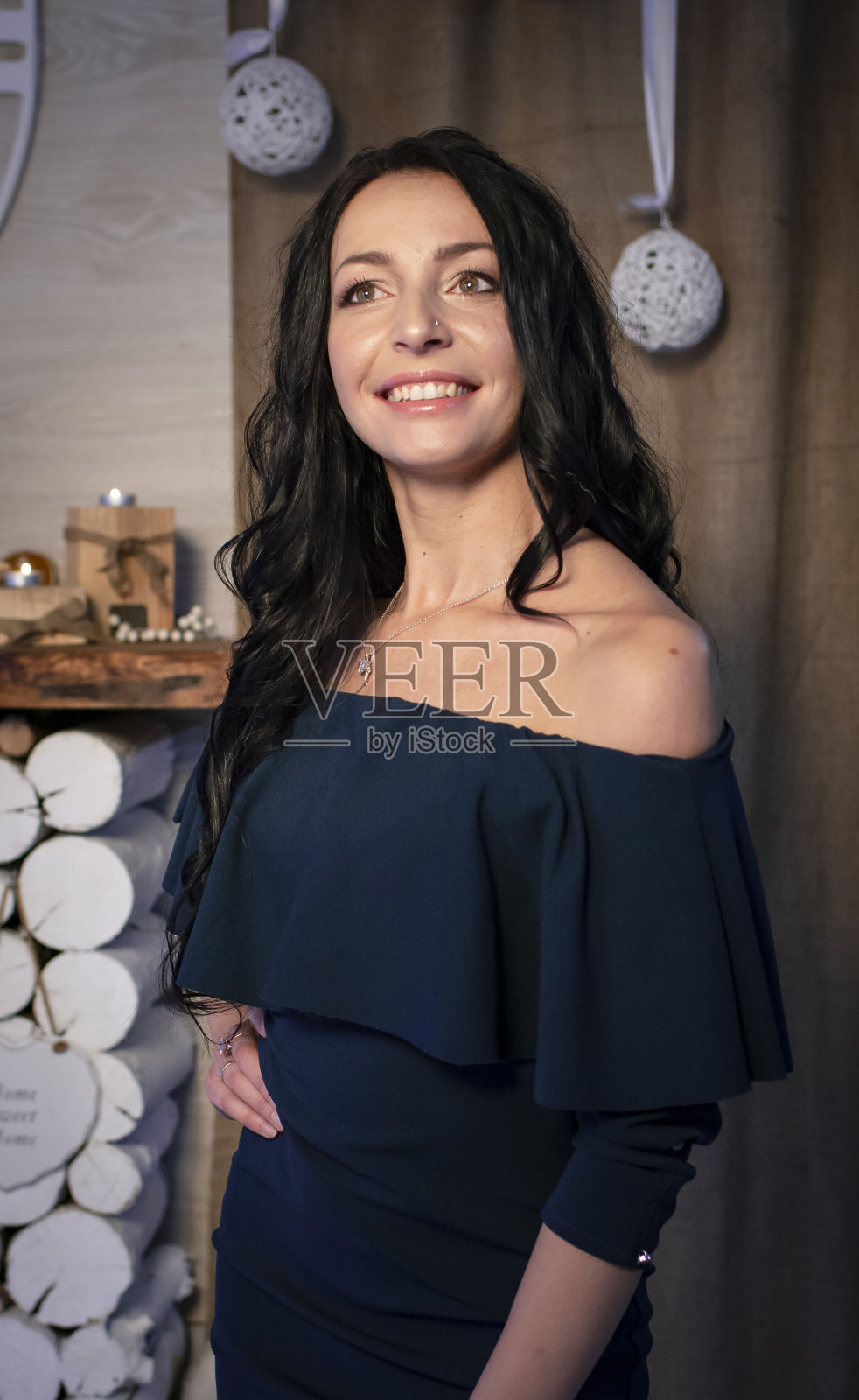 一个漂亮的女孩拿着一个玩具坐在壁炉和圣诞树旁边的地板上迎接新年照片摄影图片