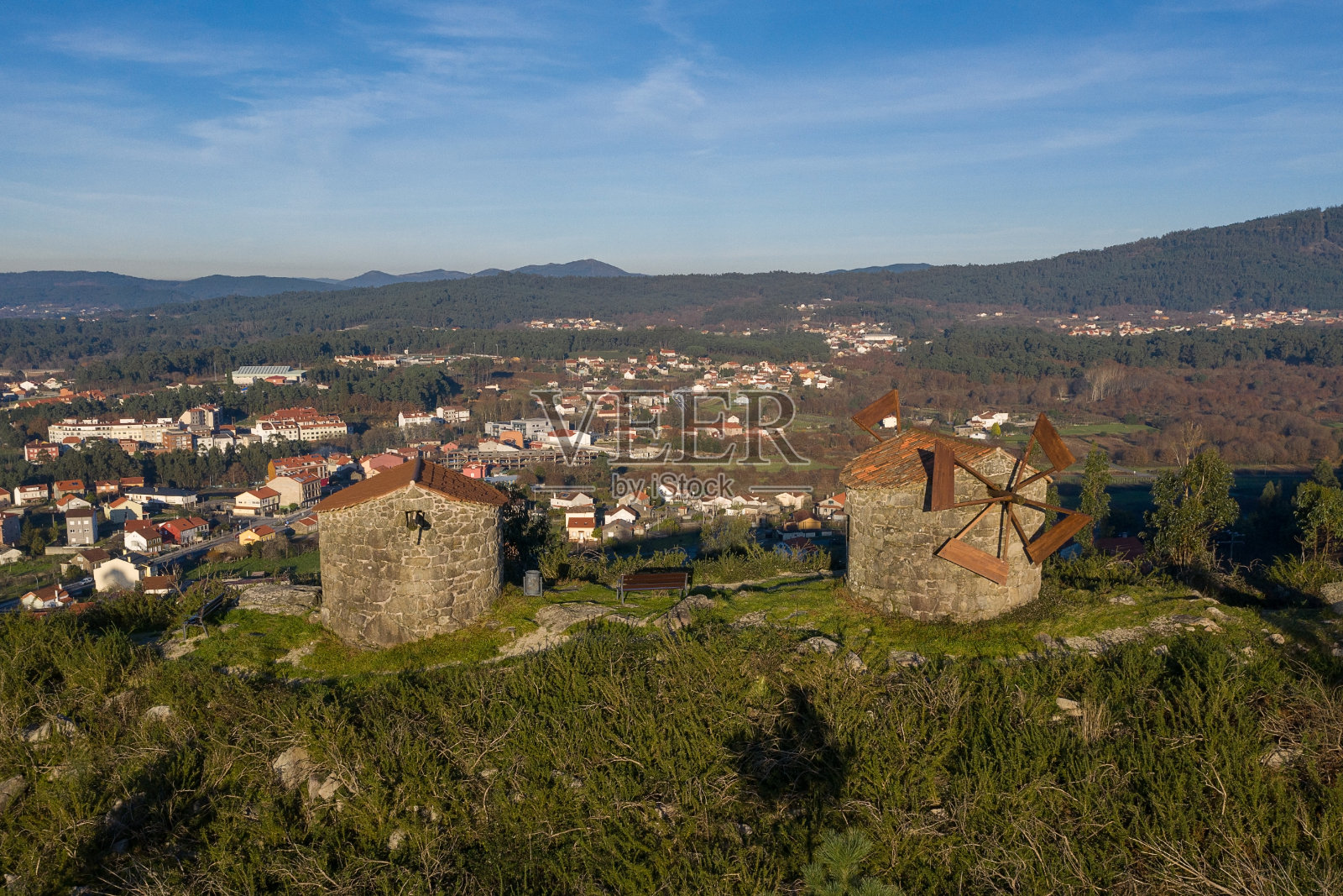 夕阳下的小山上的古老的石头风车照片摄影图片