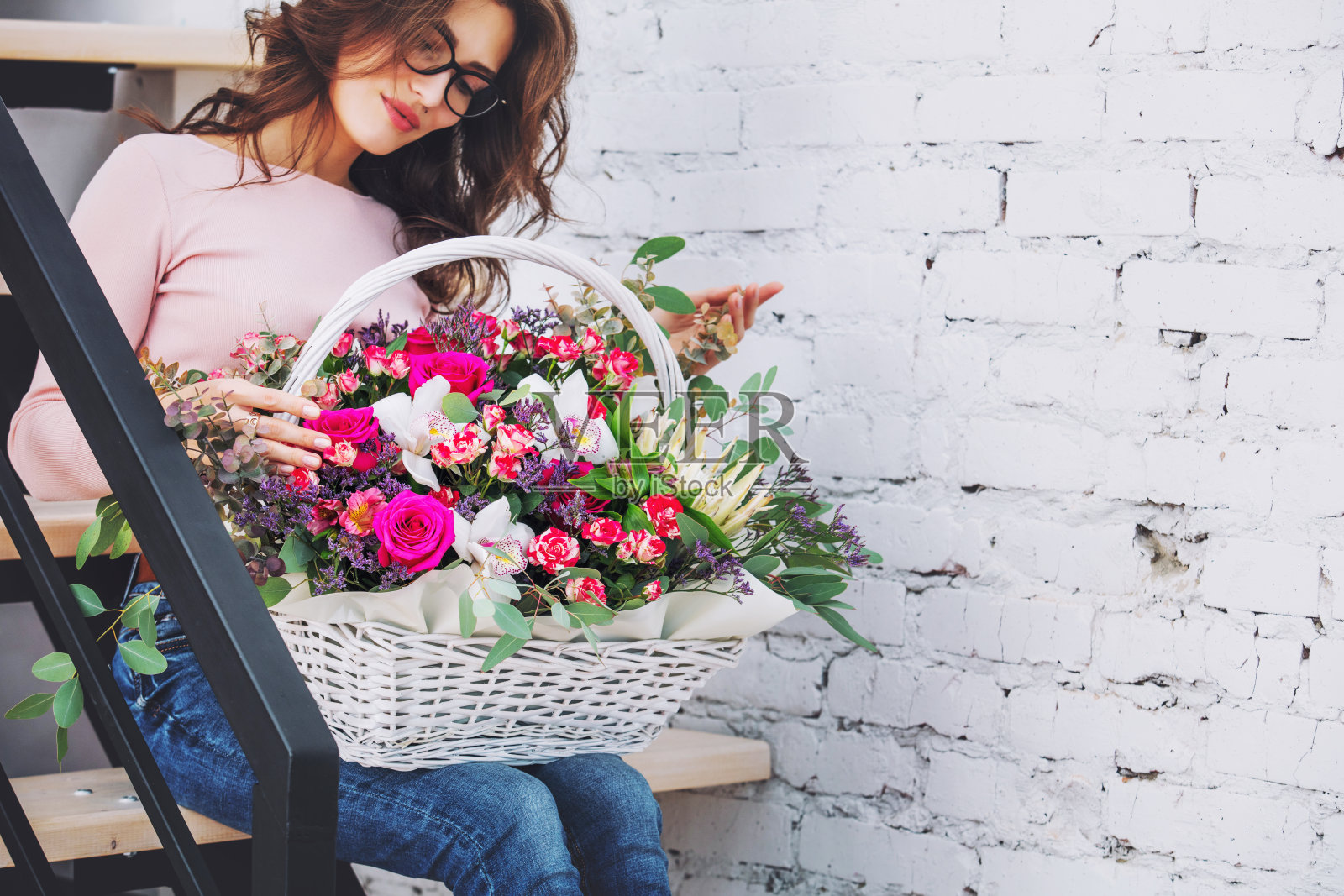 年轻的成年人美丽和快乐的女人模型与鲜花在她的手肖像在一个明亮的楼梯照片摄影图片