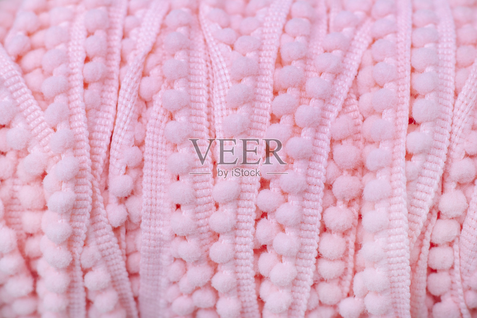 背景纹理的毛绒线与绒球。微妙的粉红色。少女的背景。照片摄影图片