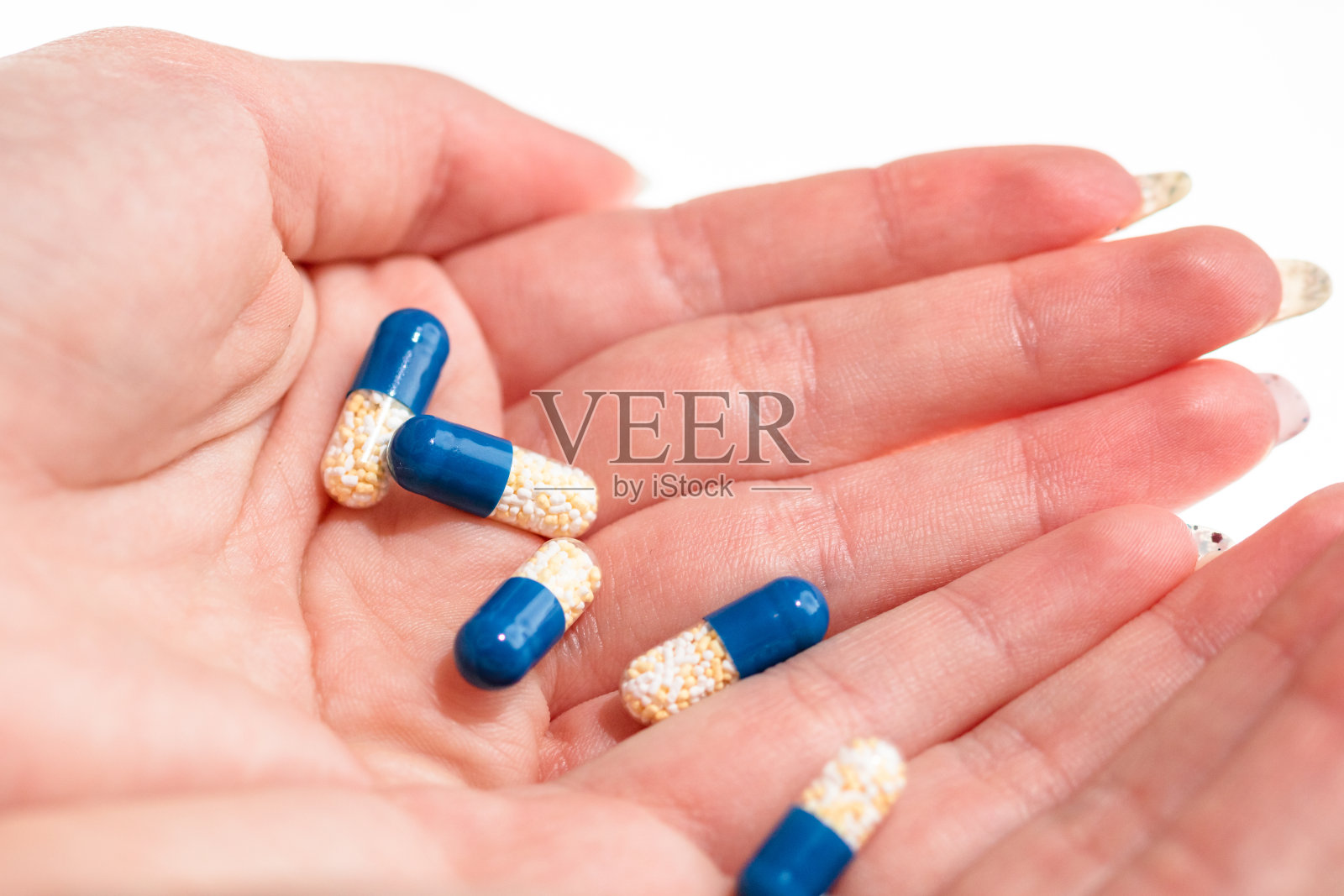 手持抗生素胶囊或止痛药，白色背景。药品概念，药丸特写，复制空间照片摄影图片