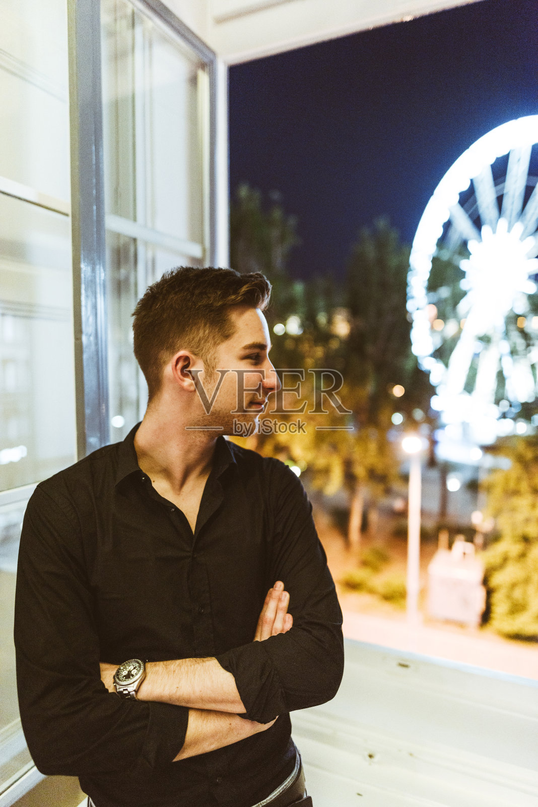 一个年轻人晚上站在窗前照片摄影图片