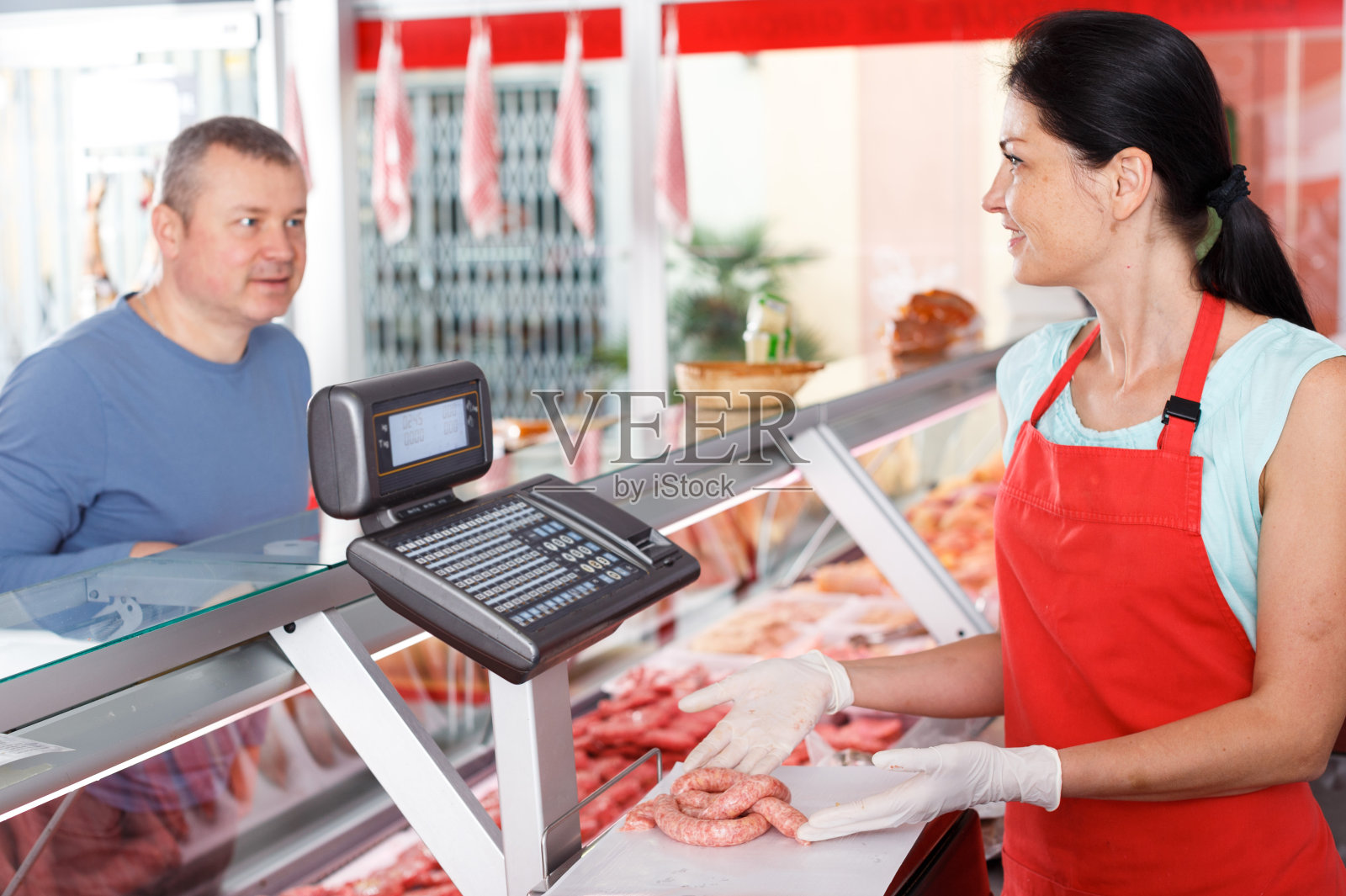 女商人在为顾客称香肠照片摄影图片