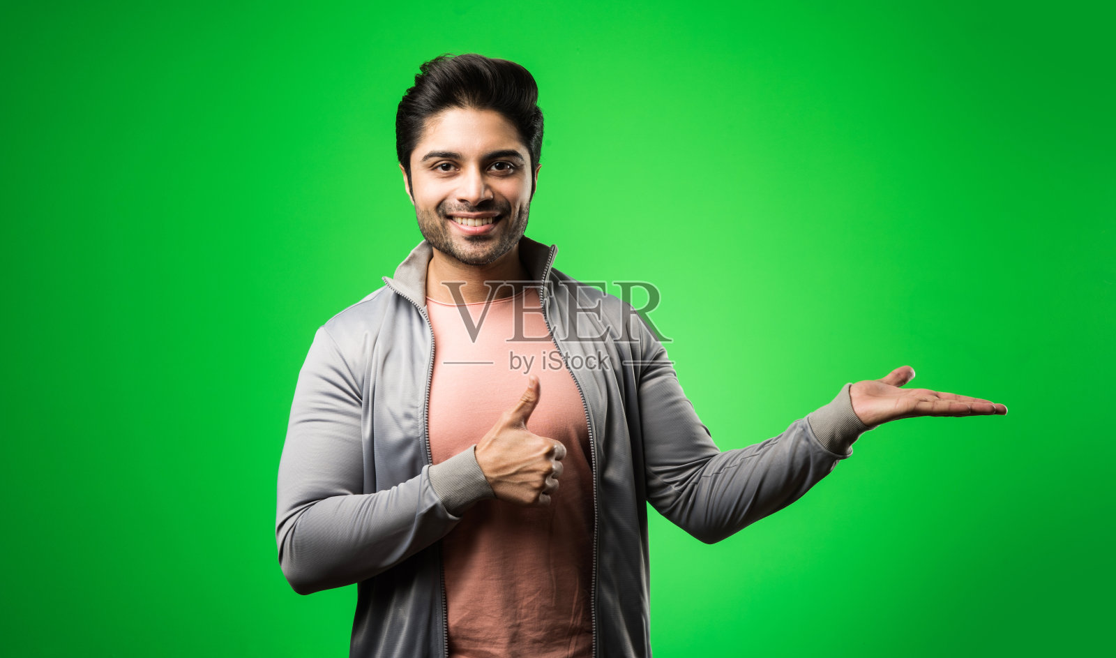 满意的印度男人用空手或手指展示、指向、展示或广告。站在绿色背景中照片摄影图片
