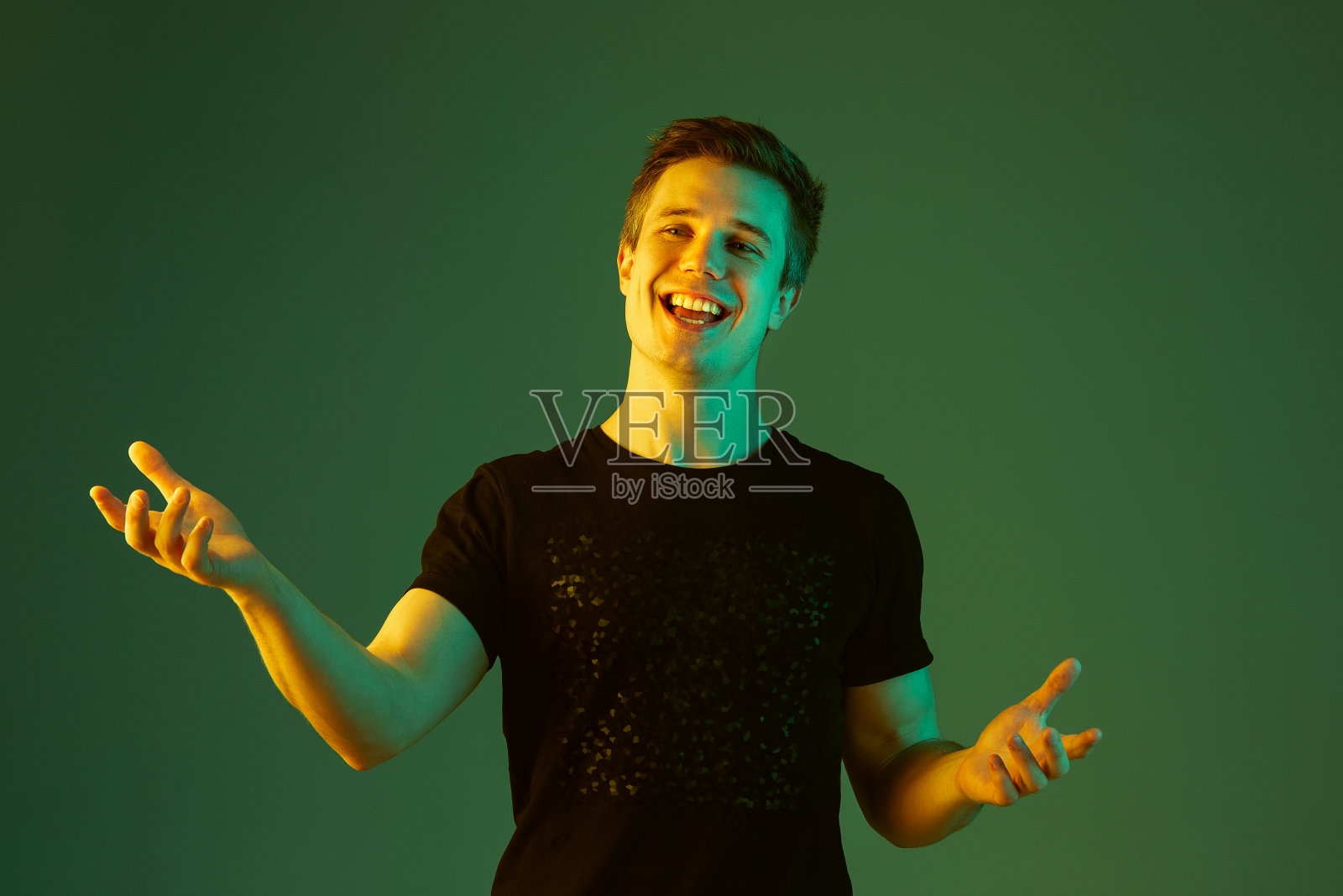 一名白人男子的肖像被隔离在霓虹灯下的绿色画室背景上照片摄影图片