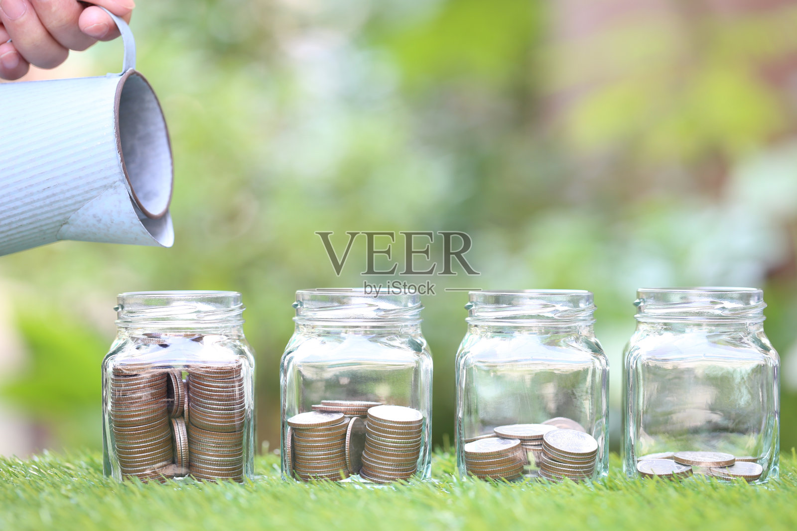 女人手持浇水壶和玻璃瓶中的硬币照片摄影图片