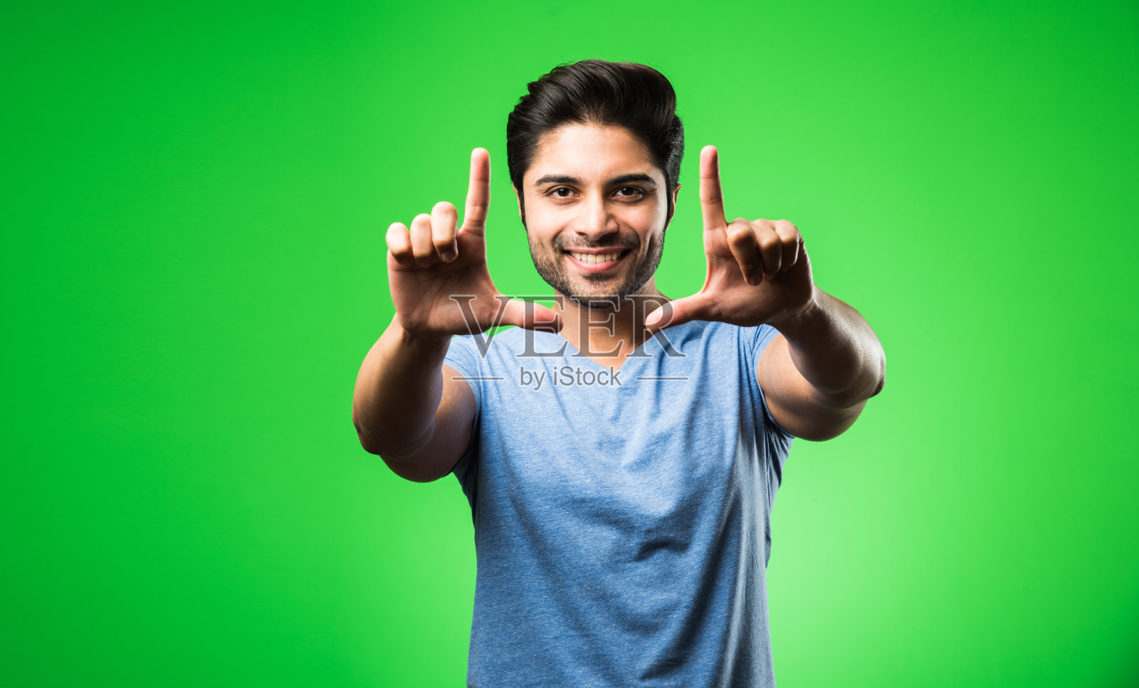 站在绿色背景前，用双手构图的印度男子照片摄影图片