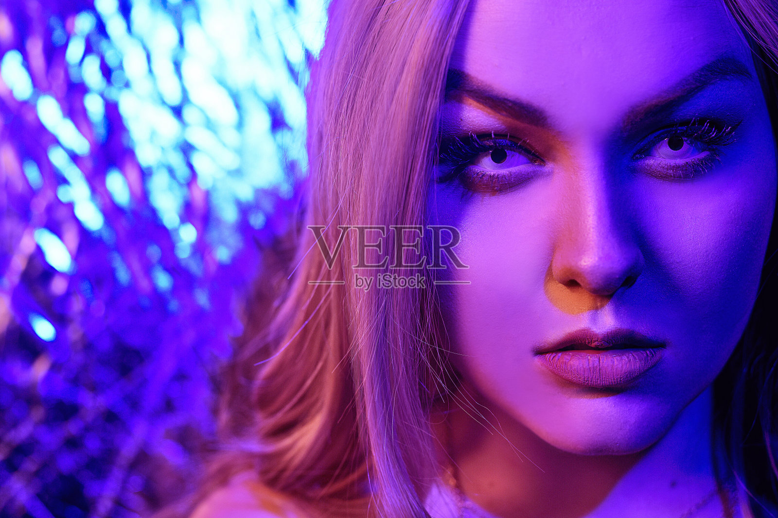 霓虹灯光下的美丽金发女郎，红蓝色抽象背景。佩戴白色镜片的女孩，霓虹色彩照片摄影图片