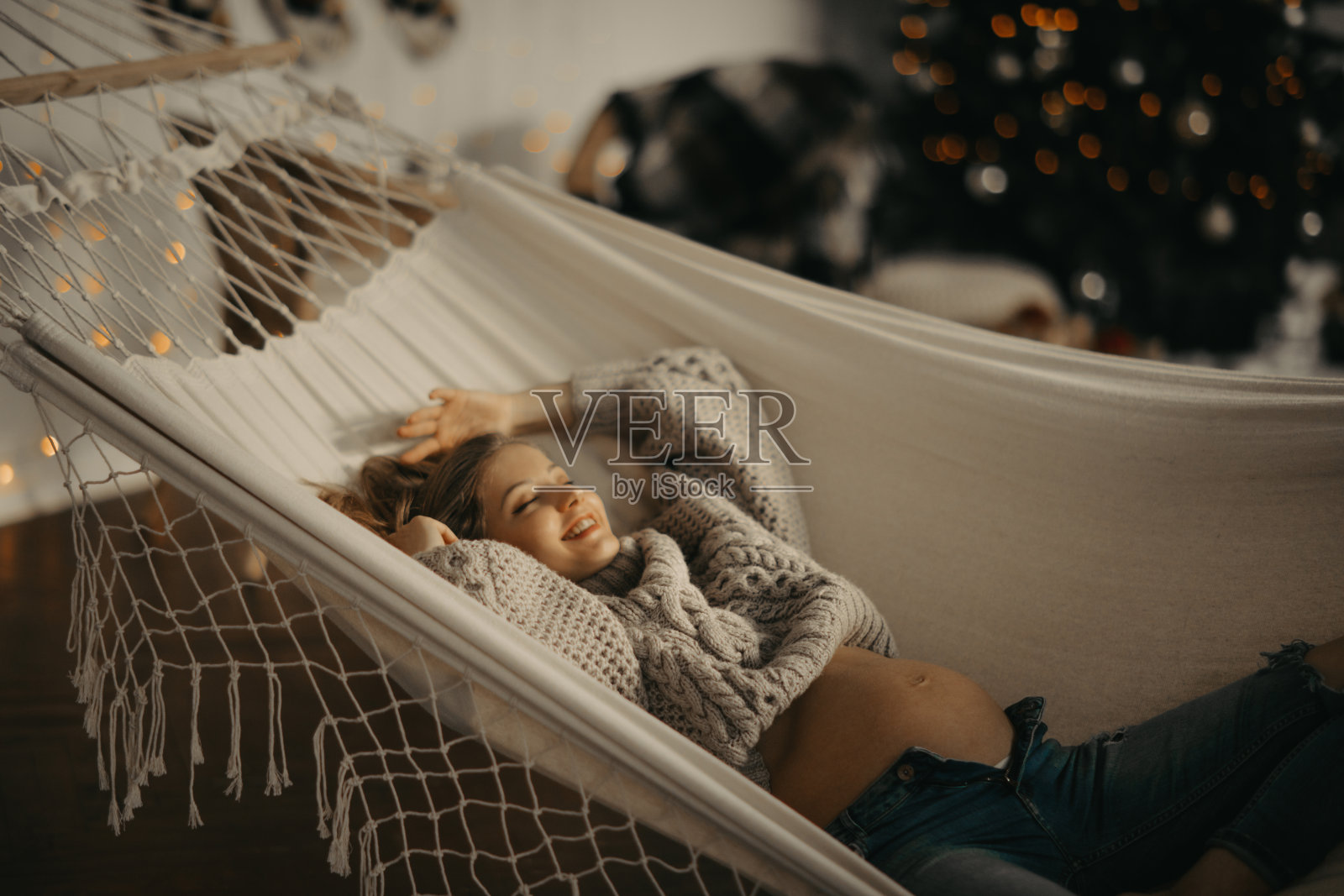 一名孕妇在吊床上休息，背景是圣诞装饰品。照片摄影图片