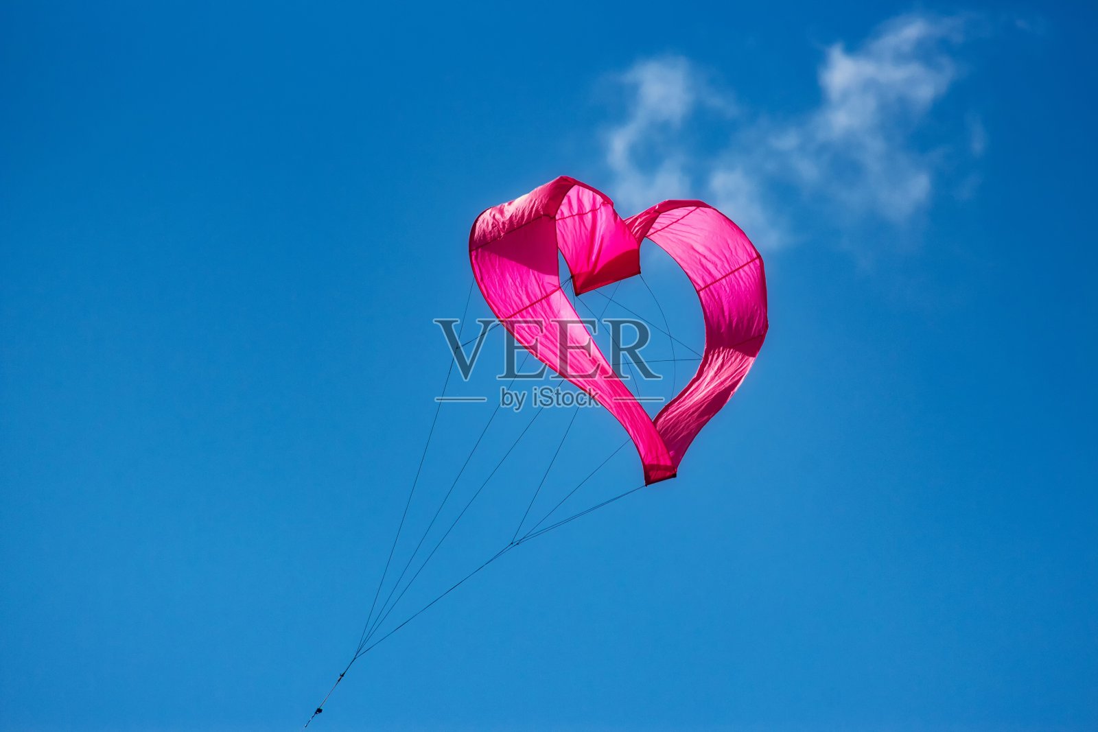 一只粉红色的心形风筝在天空中飞翔照片摄影图片