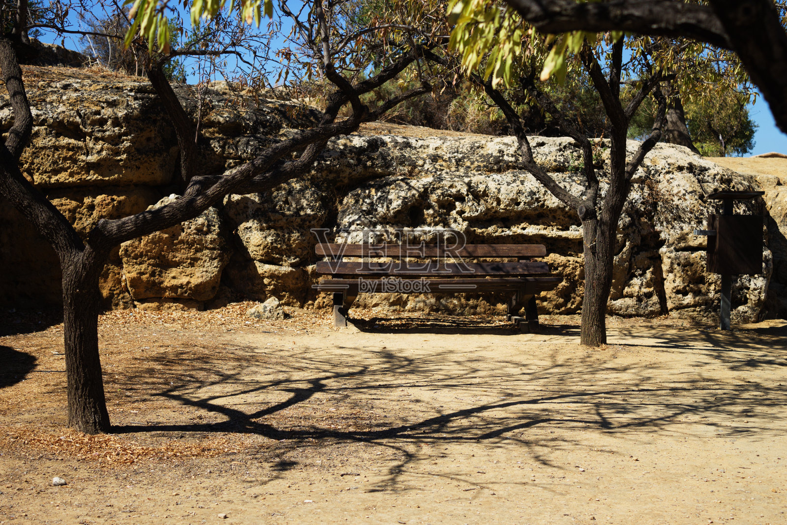 一条长凳，前面有树的阴影，背景是一堵古老的墙Valle dei Templi，阿格里琴托，意大利，西西里照片摄影图片