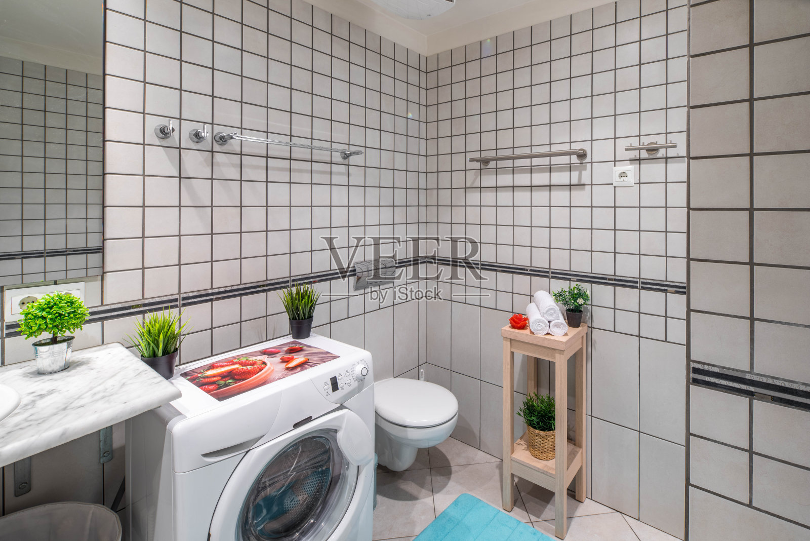 浴室内部，墙壁和地板上铺着灰色瓷砖。洗衣机。照片摄影图片