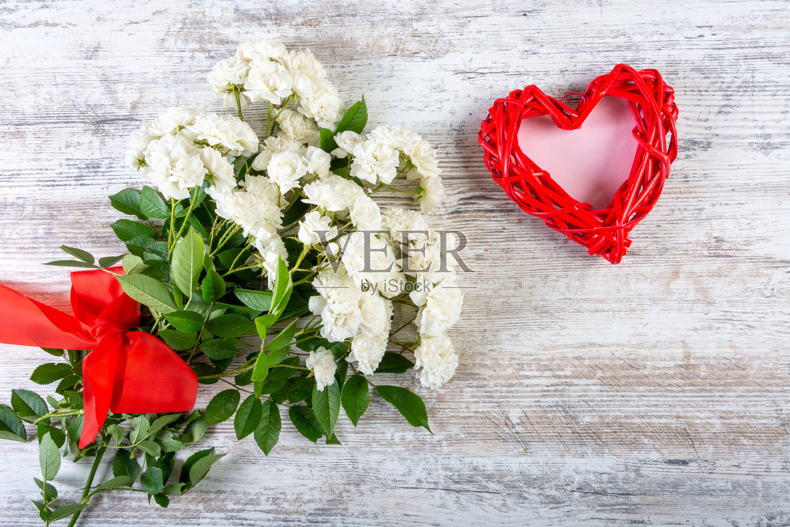 一束白玫瑰和一颗心形象征着铭文。照片摄影图片