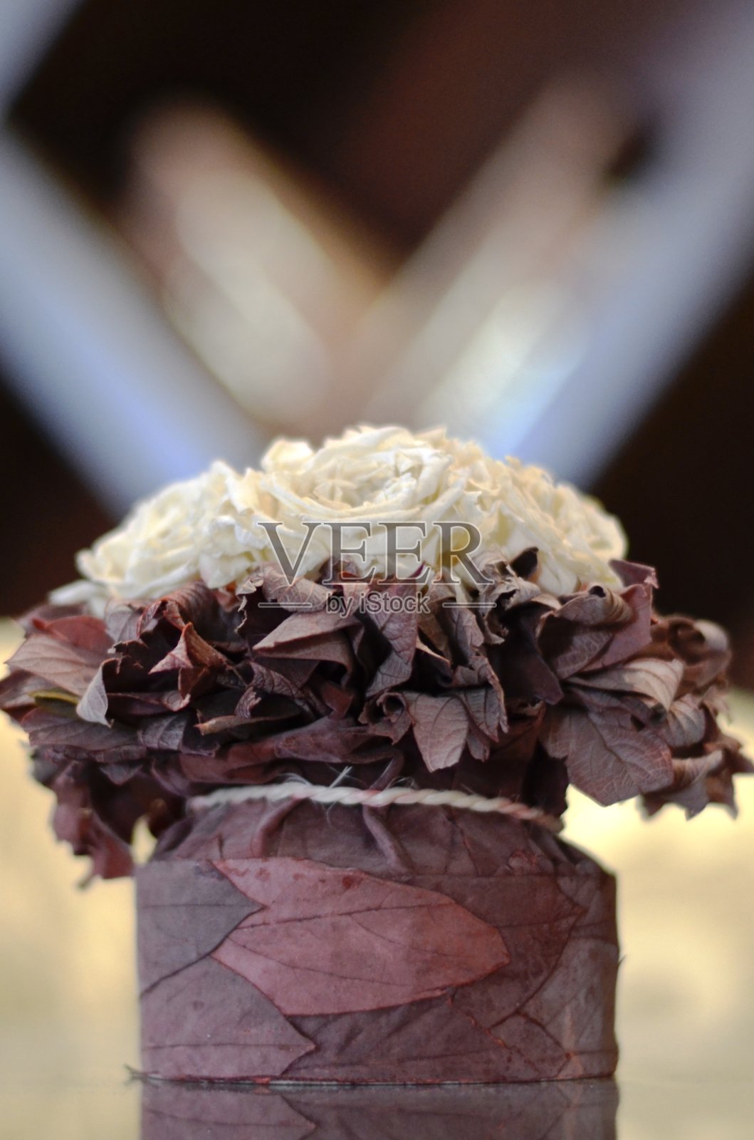 半束装饰的白玫瑰，半束垂直的紫红色叶子在一个明亮的背景。照片摄影图片