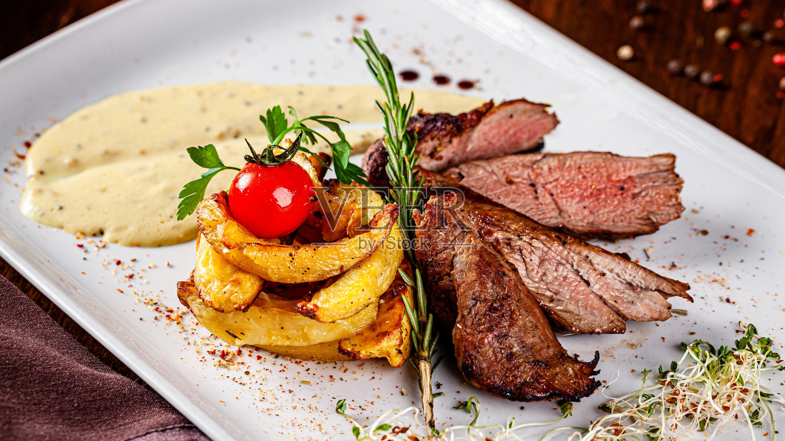 意大利菜。猪里脊牛排，配土豆和半汁酱汁。漂亮的餐厅在一个白色的盘子。背景图像，拷贝空间照片摄影图片