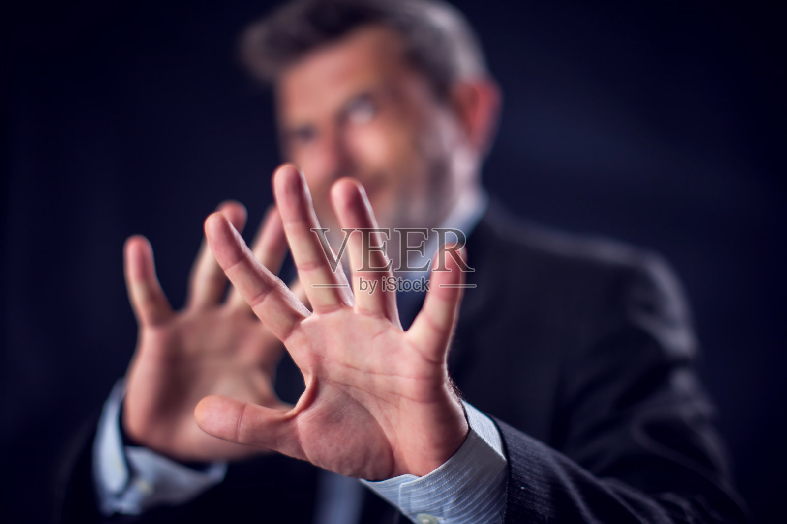 身穿西装的商人在黑色背景前用手势示意停止照片摄影图片