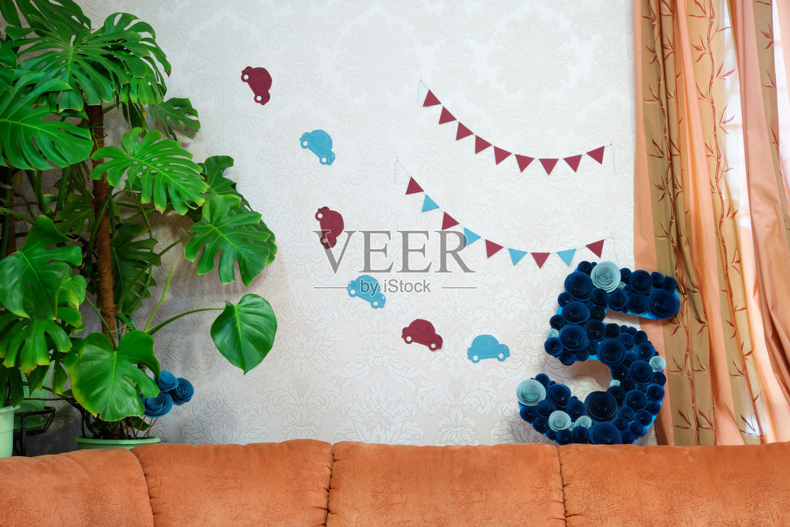 给孩子过生日的装饰品。手工制作的蓝色五号生日礼物，上面装饰着纸花，还有一辆纸车。照片摄影图片