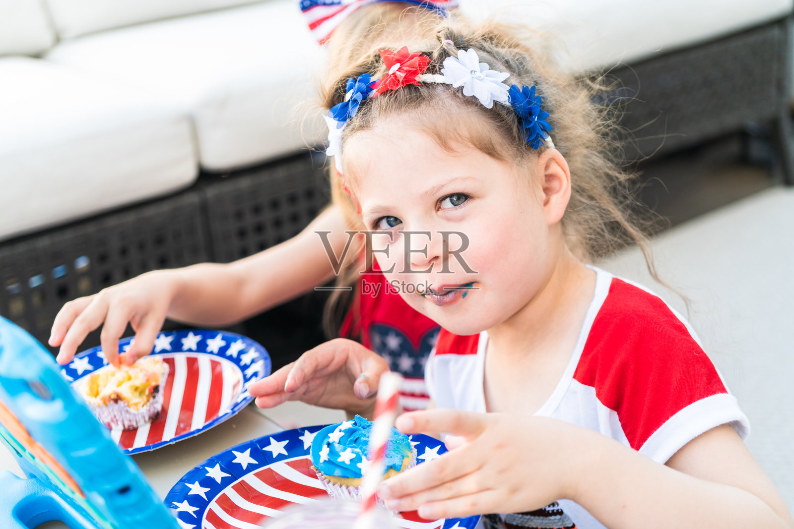 两个穿着7月4日服装的小女孩吃纸杯蛋糕照片摄影图片
