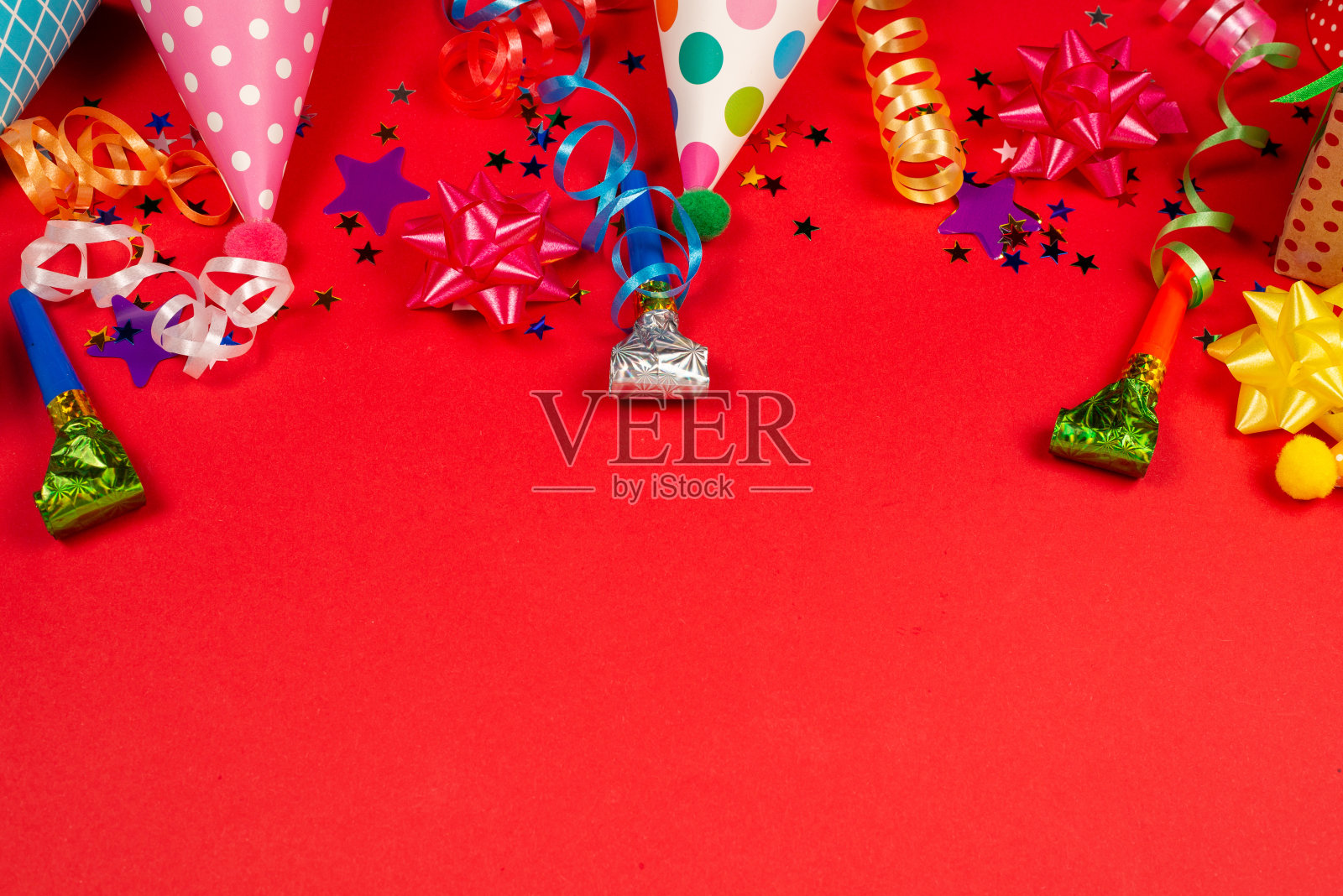 喜庆的金色和紫色星星五彩纸屑和礼物，红色背景上的生日帽。照片摄影图片