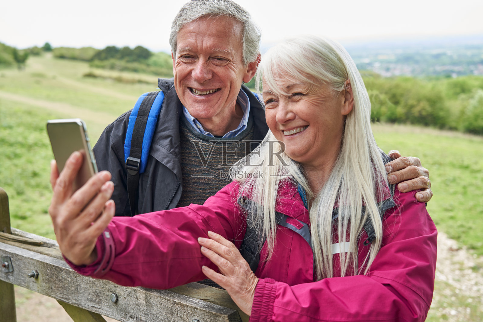 微笑的老年夫妇在乡村徒步，站在门口用手机自拍照片摄影图片