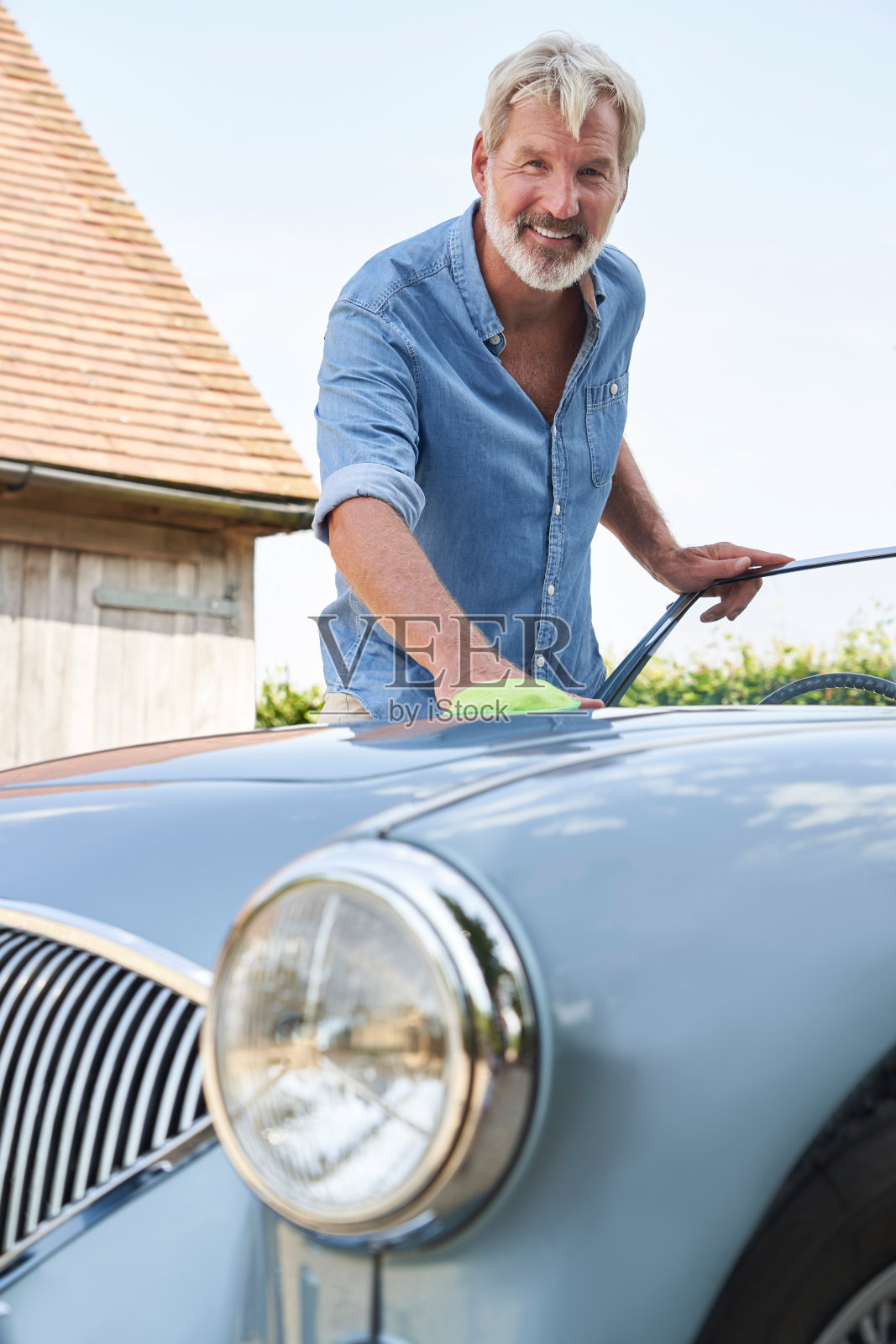 年长的男人在户外家里擦拭修复后的经典跑车肖像照片摄影图片