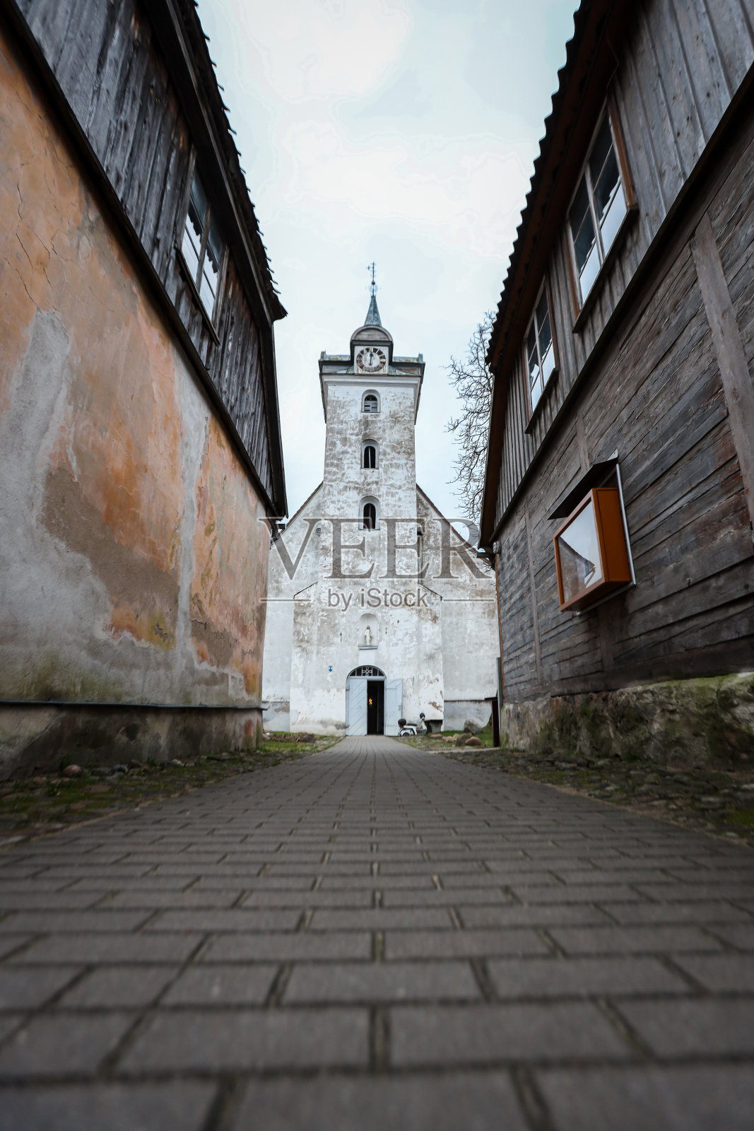 美丽的白色老教堂位于两个老房子之间照片摄影图片