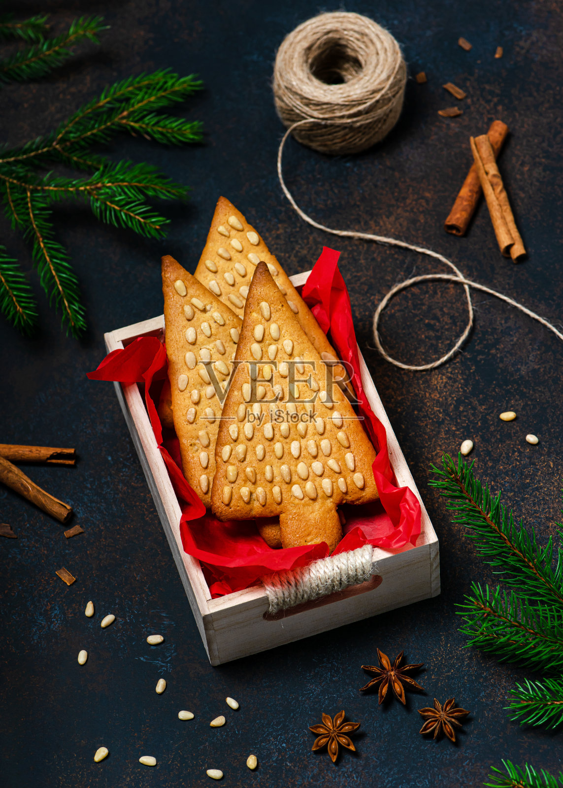 传统的姜饼蜂蜜饼干圣诞树形状和松子在白色木箱。照片摄影图片