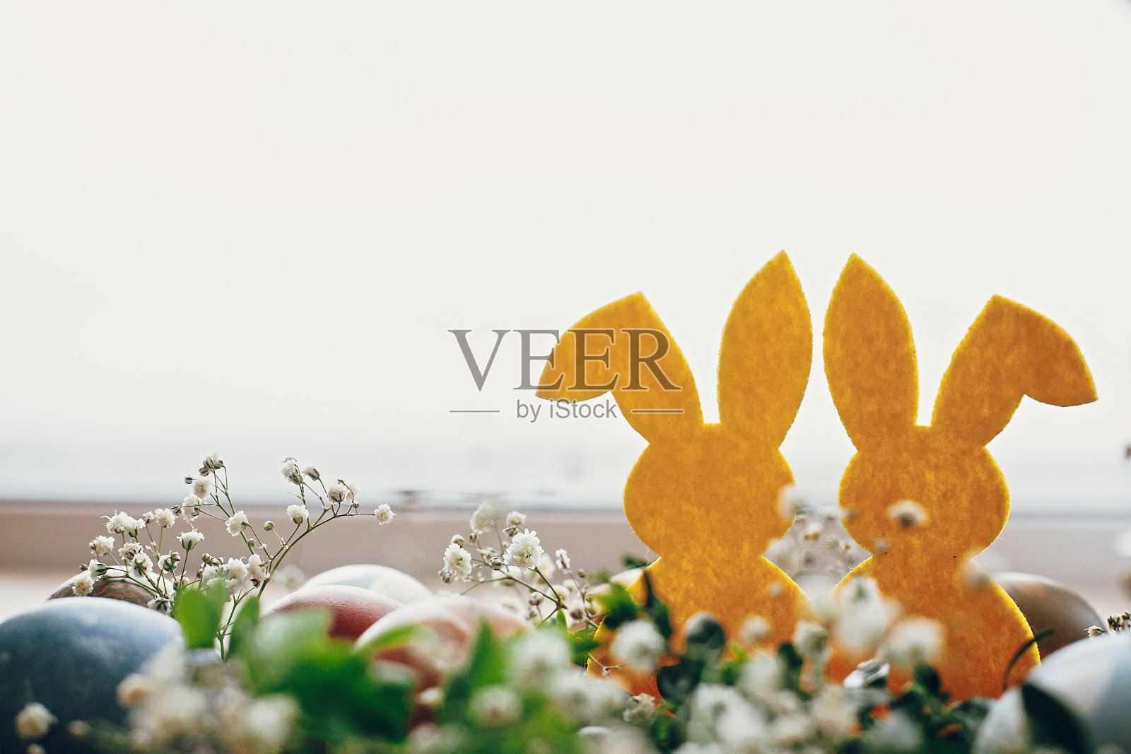 复活节快乐。时尚的复活节彩蛋，质朴的木桌上鸟窝中的黄色兔子，文字空间。天然染色的复活节彩蛋和兔子灯装饰照片摄影图片