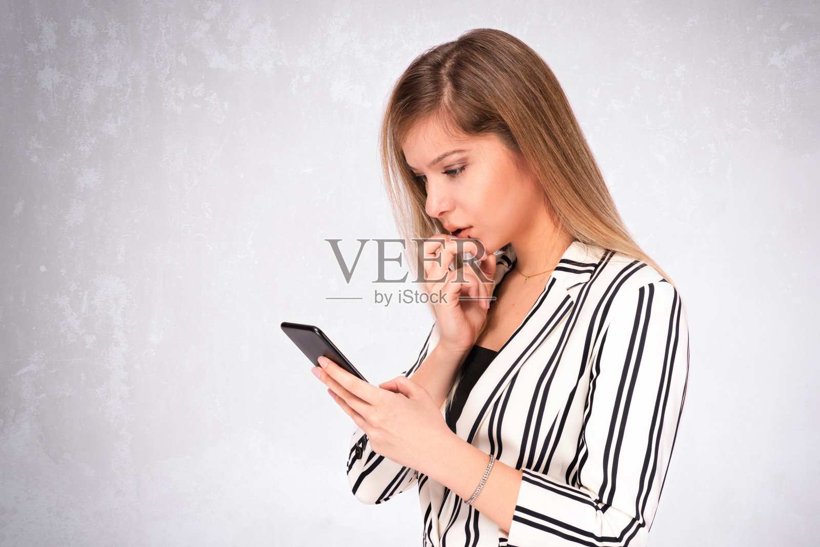 漂亮的金发商务女性穿着西装使用她的智能手机和查看她的社交媒体帐户照片摄影图片