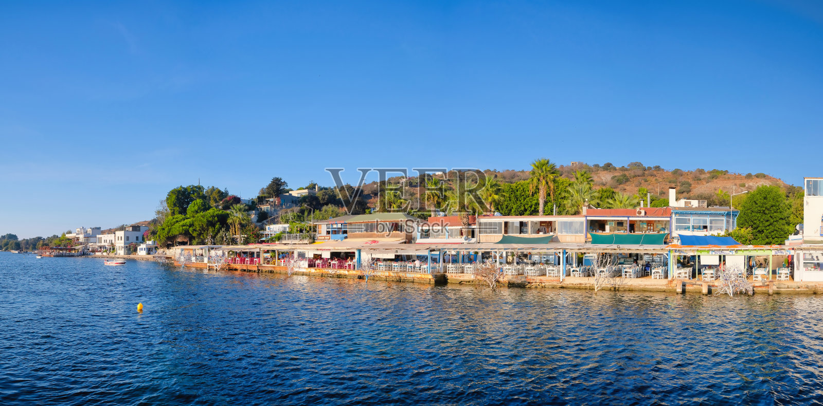 博德鲁姆Gumusluk海滩上的餐厅和三角梅花。在美丽的爱琴海附近的博德鲁姆镇，五颜六色的椅子、桌子和鲜花。照片摄影图片