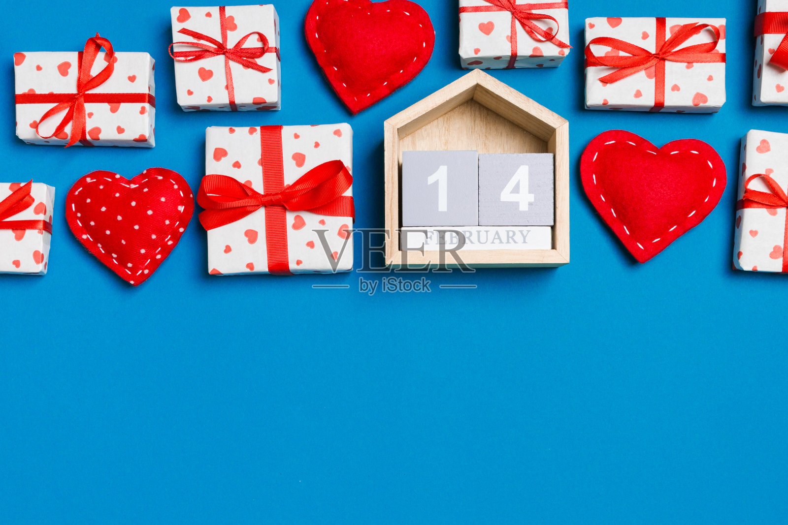 礼品盒、木制日历和红色纺织心形在彩色背景上的节日组合，为您的设计留有空白空间。2月14日。情人节概念的顶视图照片摄影图片